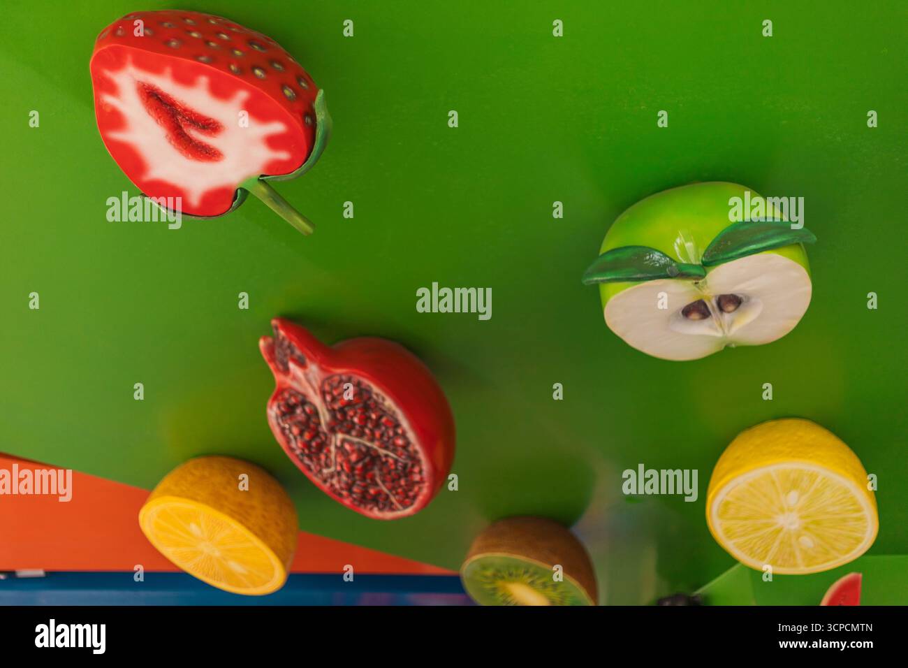 Auf einem Markt werden verschiedene Fruchtformen auf einer hellgrünen Oberfläche präsentiert. Das Display umfasst Erdbeeren, Äpfel, Zitronen, Granatäpfel und Creatin Stockfoto