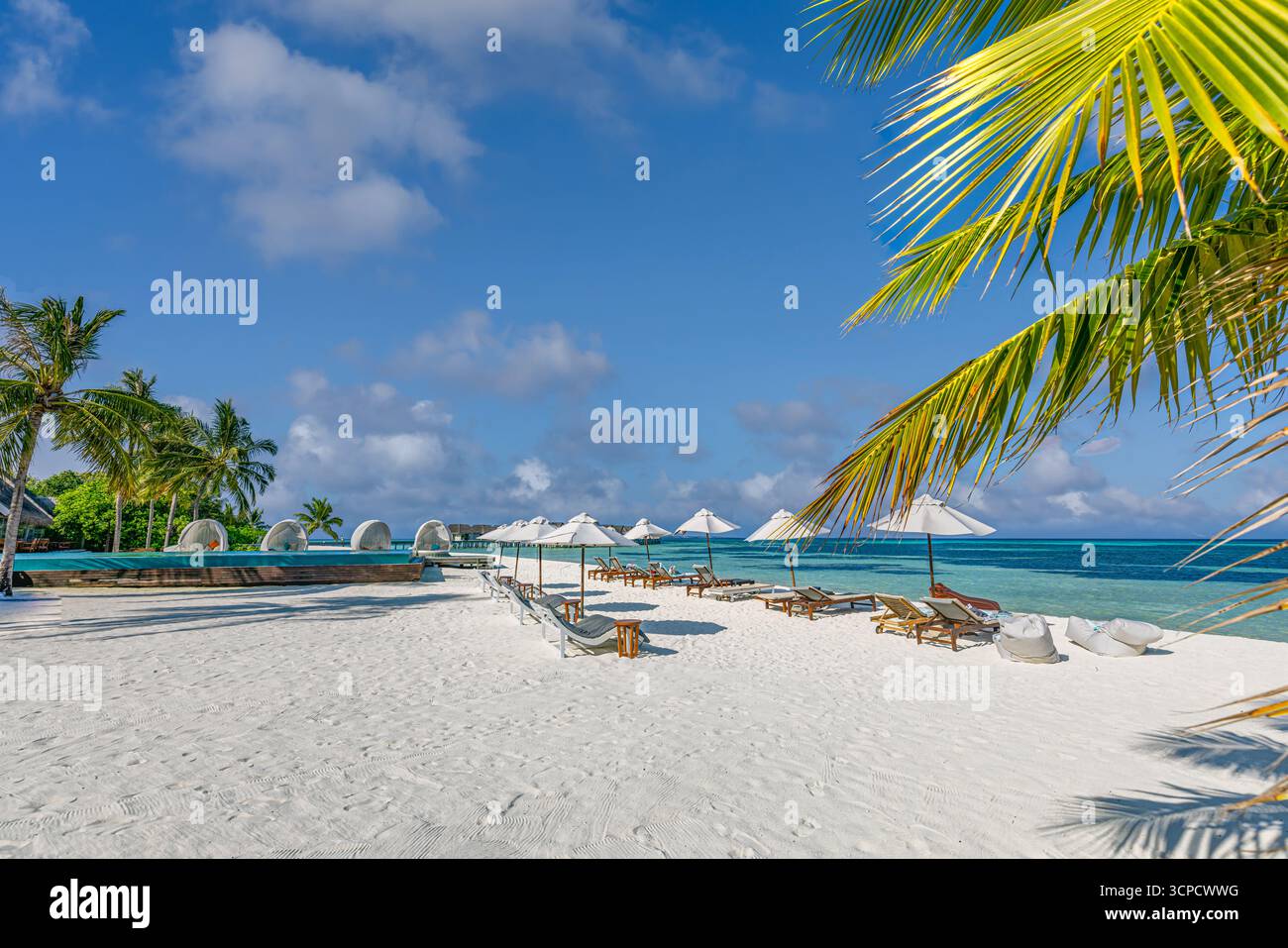 Luxus Sommer Strand Resort Freizeit Stühle Sonnenschirme weißer Sand blaues Meer Wasser sonniger Himmel Horizont tropischer Insel Urlaub malerische Landschaft Hintergrund Stockfoto