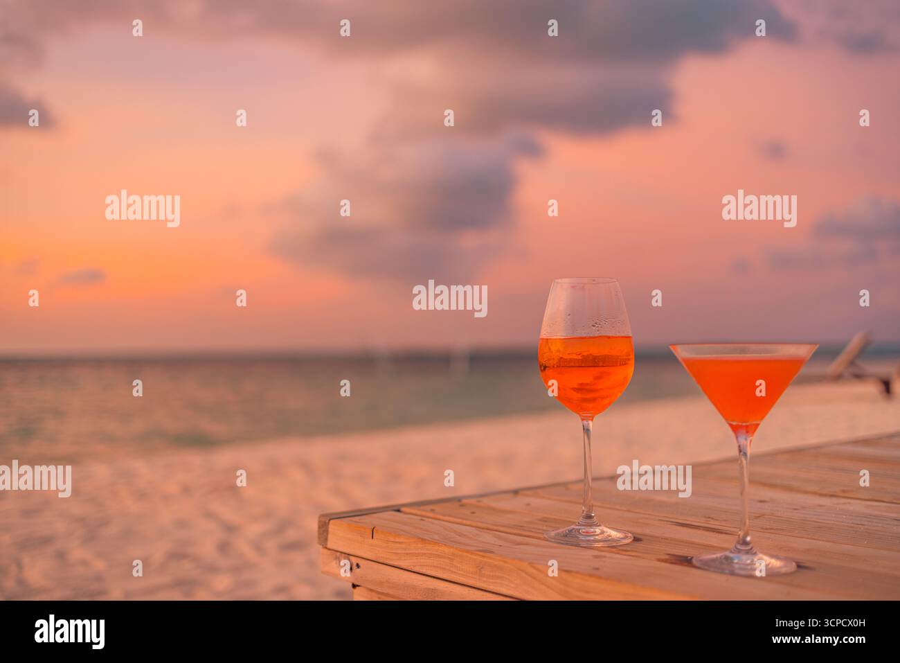 Romantischer Sonnenuntergang Himmel Strand Cocktails Meerblick zwei Hände heben aperol Gläser tropische Insel Sommer Vibe warmer Himmel lebendige Meer Horizont Reiseszene Stockfoto