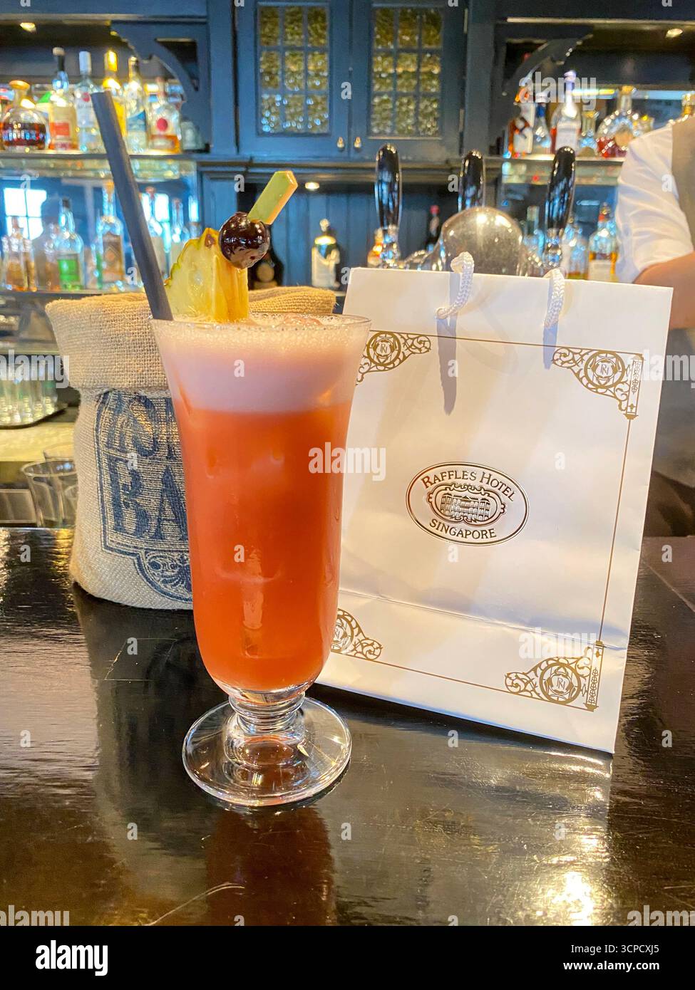 Ein ÔSling CocktailÕ-Glas, gefüllt bis zum Rand des berühmten ÔSingapore SlingÕ-Cocktailgetränks, garniert mit einem Likör gewürzten Stück Ananas und ch Stockfoto