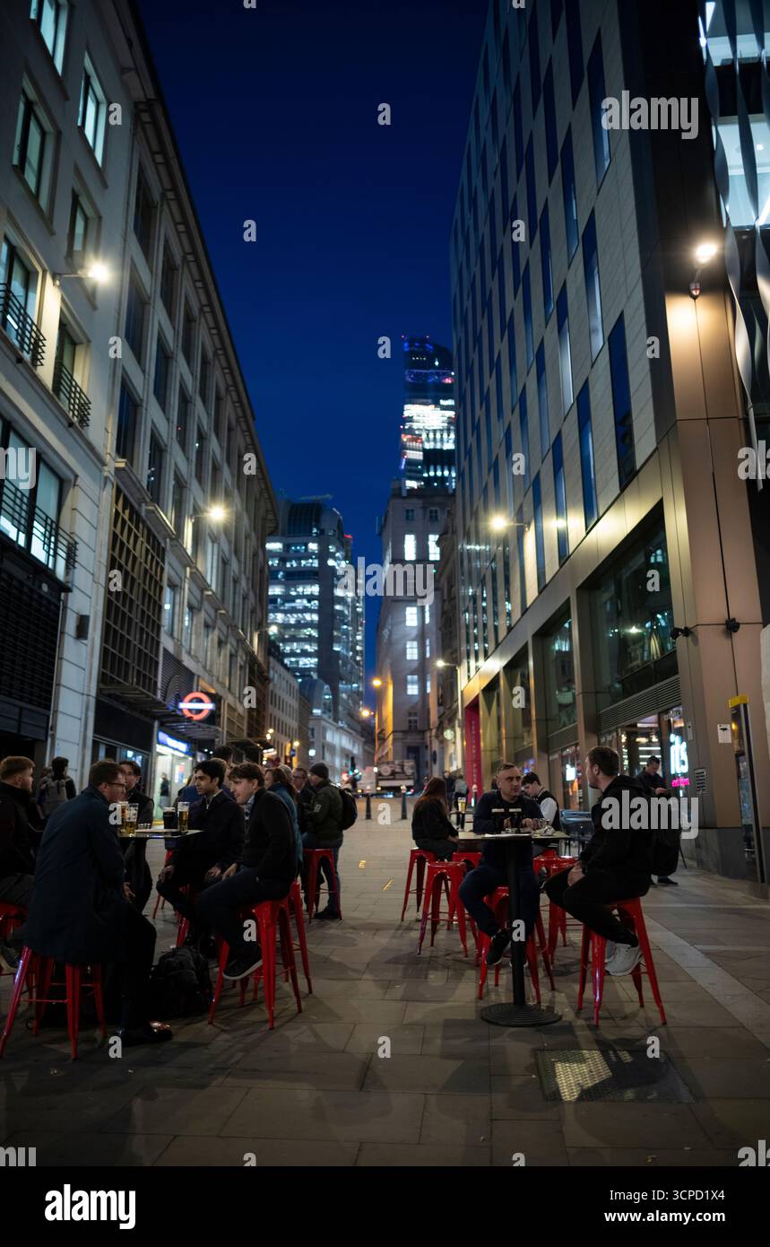 Stadtarbeiter genießen einen späten Abend bei einem Drink, während sie draußen an einer Bar in Monument, City of London, England, Großbritannien sitzen Stockfoto