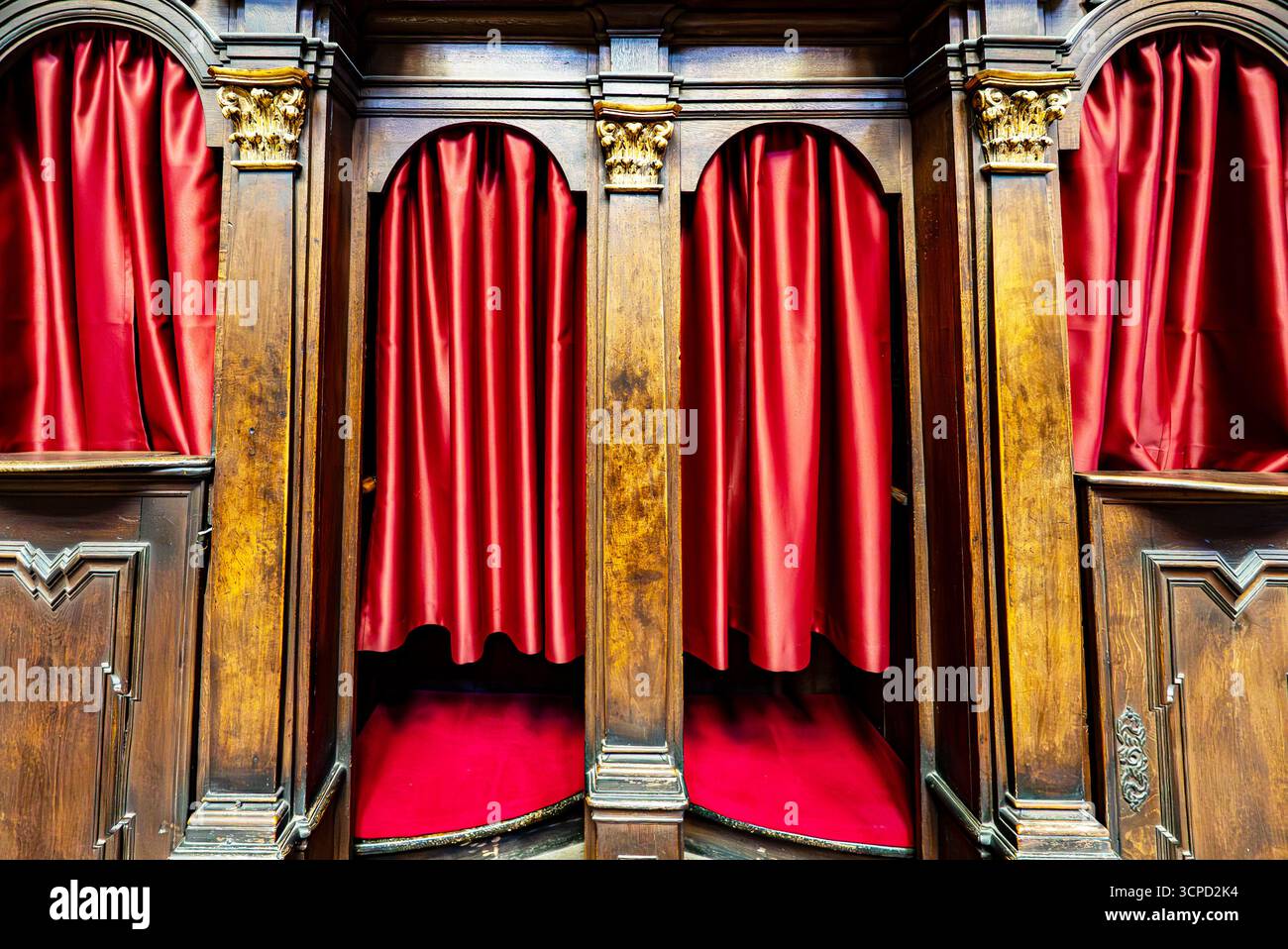 Hölzerne Beichtkabinen mit roten Vorhängen in der Kirche. Stockfoto