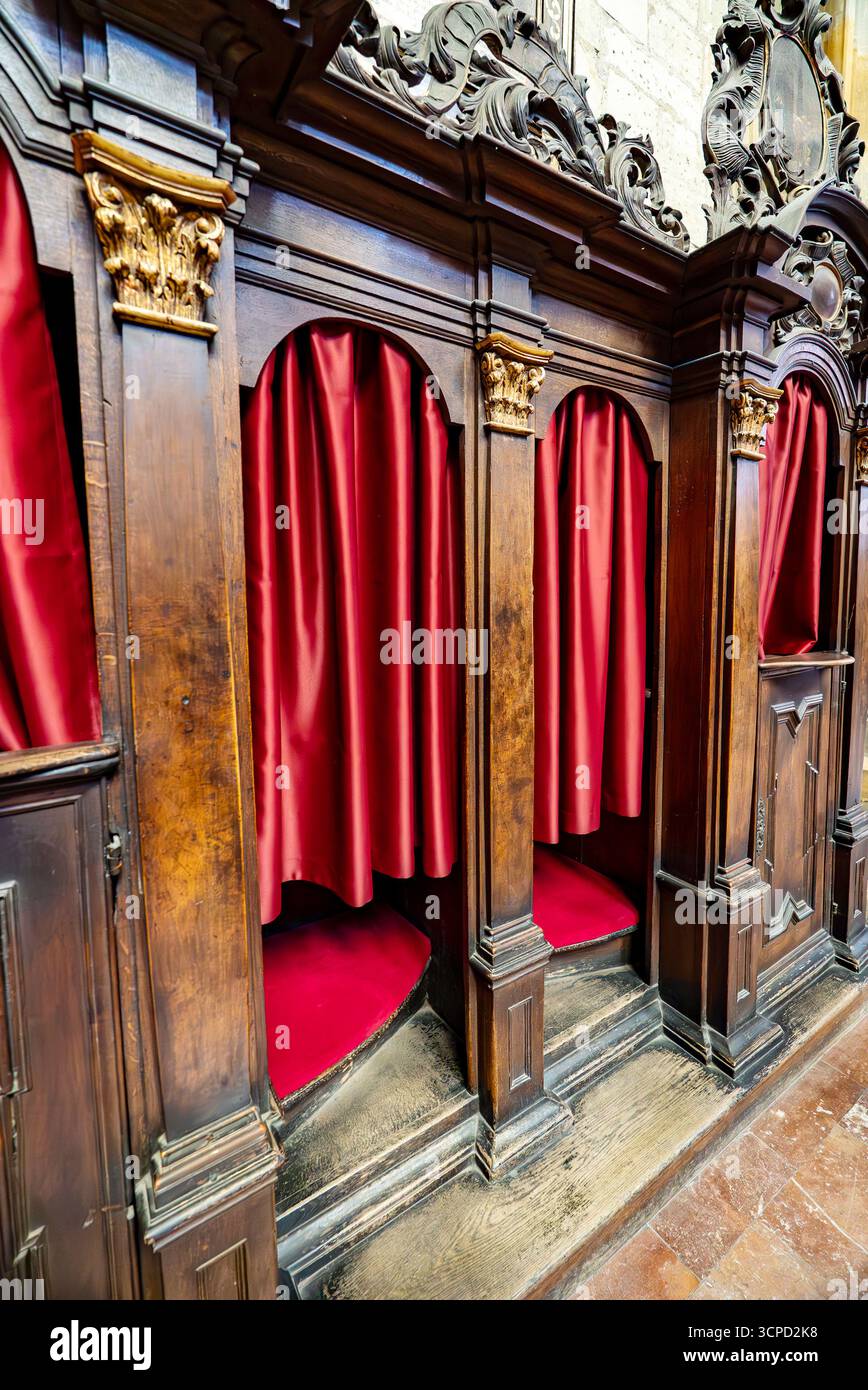 Hölzerne Beichtkabinen mit roten Vorhängen in der Kirche. Stockfoto