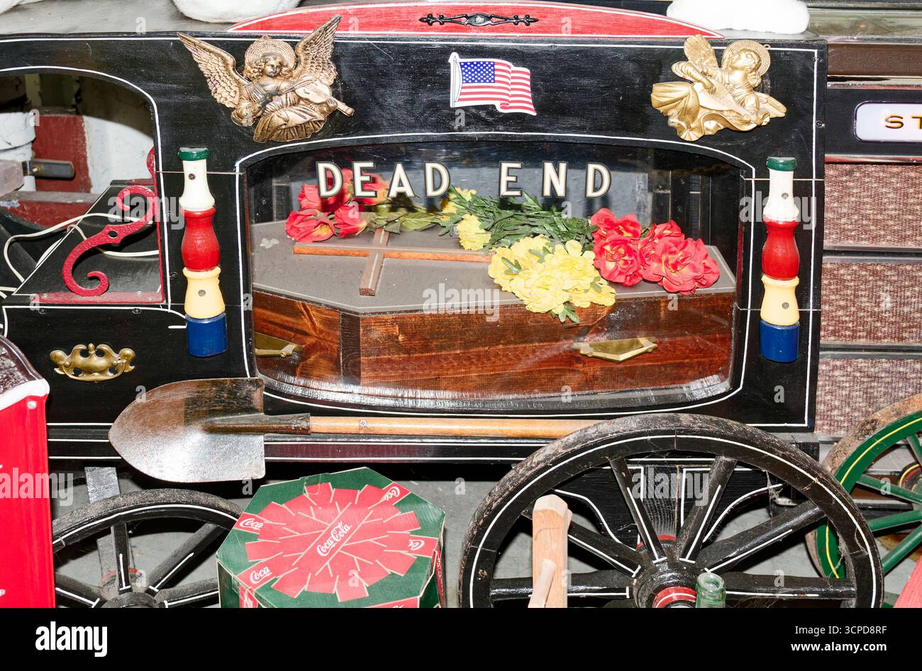 Antikes Bestattungsauto klein, Seitenfenster, Blumen auf Sarg, Schaufel draußen, Engelsdekoration, US-Flagge, Text Sackgasse, American Treasure Tour Museum, PE Stockfoto