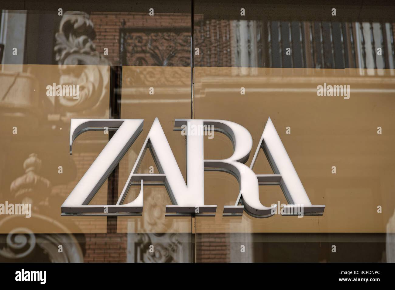 Nahaufnahme des ZARA-Logos an Einem Schaufenster, hinter dem die Reflexion Eines historischen europäischen Gebäudes zu sehen ist Stockfoto