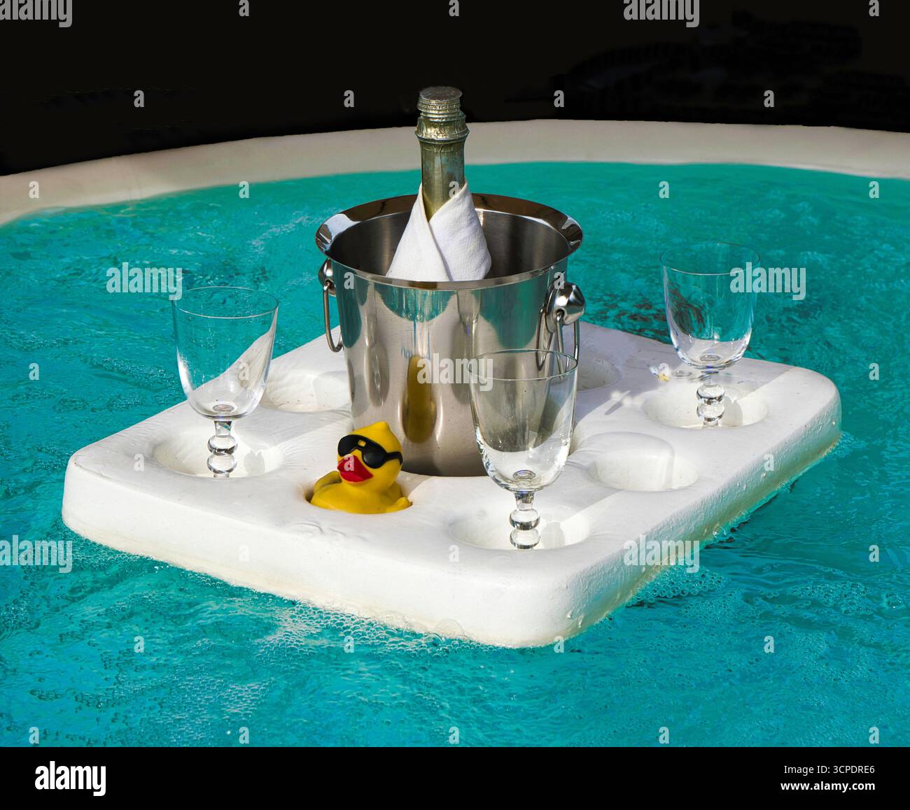 Eine Flasche Champagner in einem Eimer mit Gläsern und eine Spielzeugente, die auf einem Polyän-Floß in einem Restaurant in Deutschland schwimmt Stockfoto