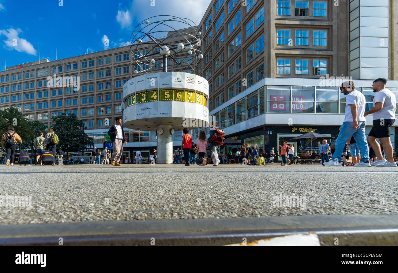 Weitwinkelaufnahme der Weltzeituhr auf dem Alexanderplatz mit Fußgängern und Stadtleben in Berlin Mitte an einem sonnigen Tag. Stockfoto