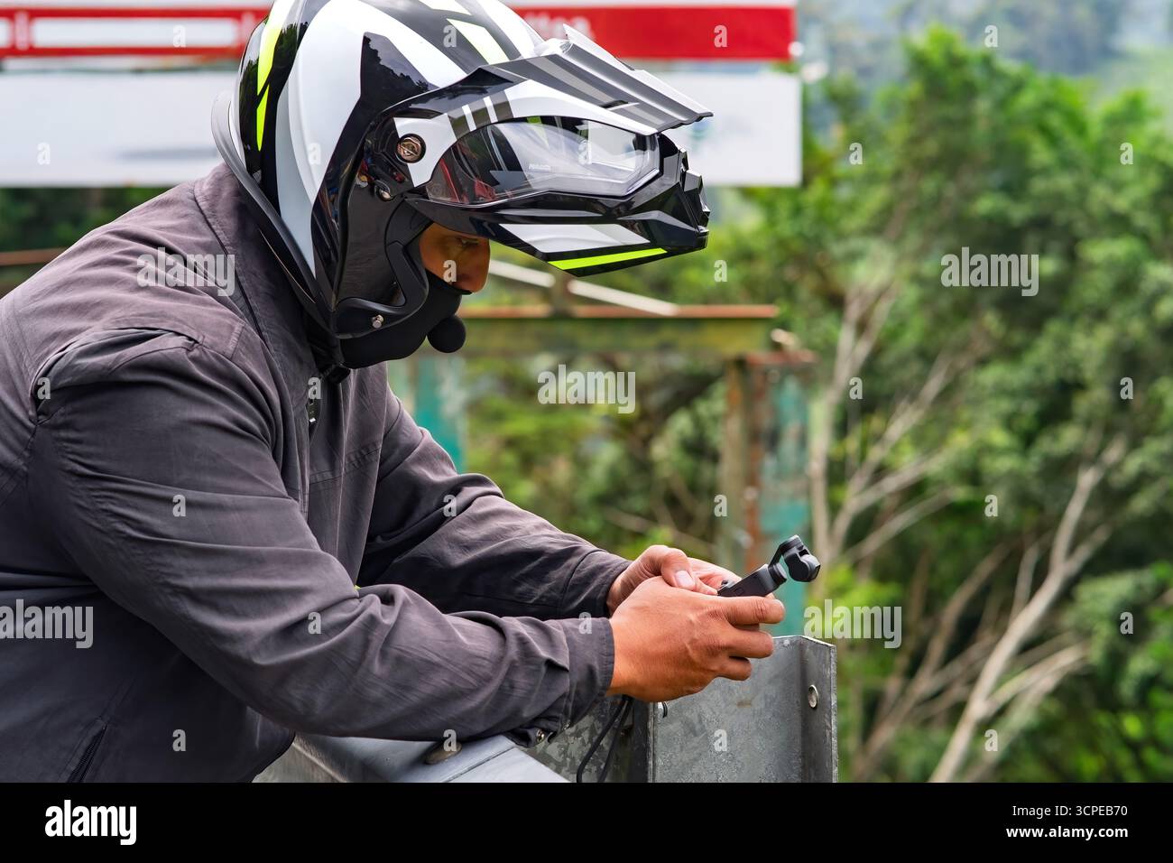 Mann mit Helm, der im Freien Video- und Fotoaufnahmen macht. Das Konzept des Privatforschers. Stockfoto