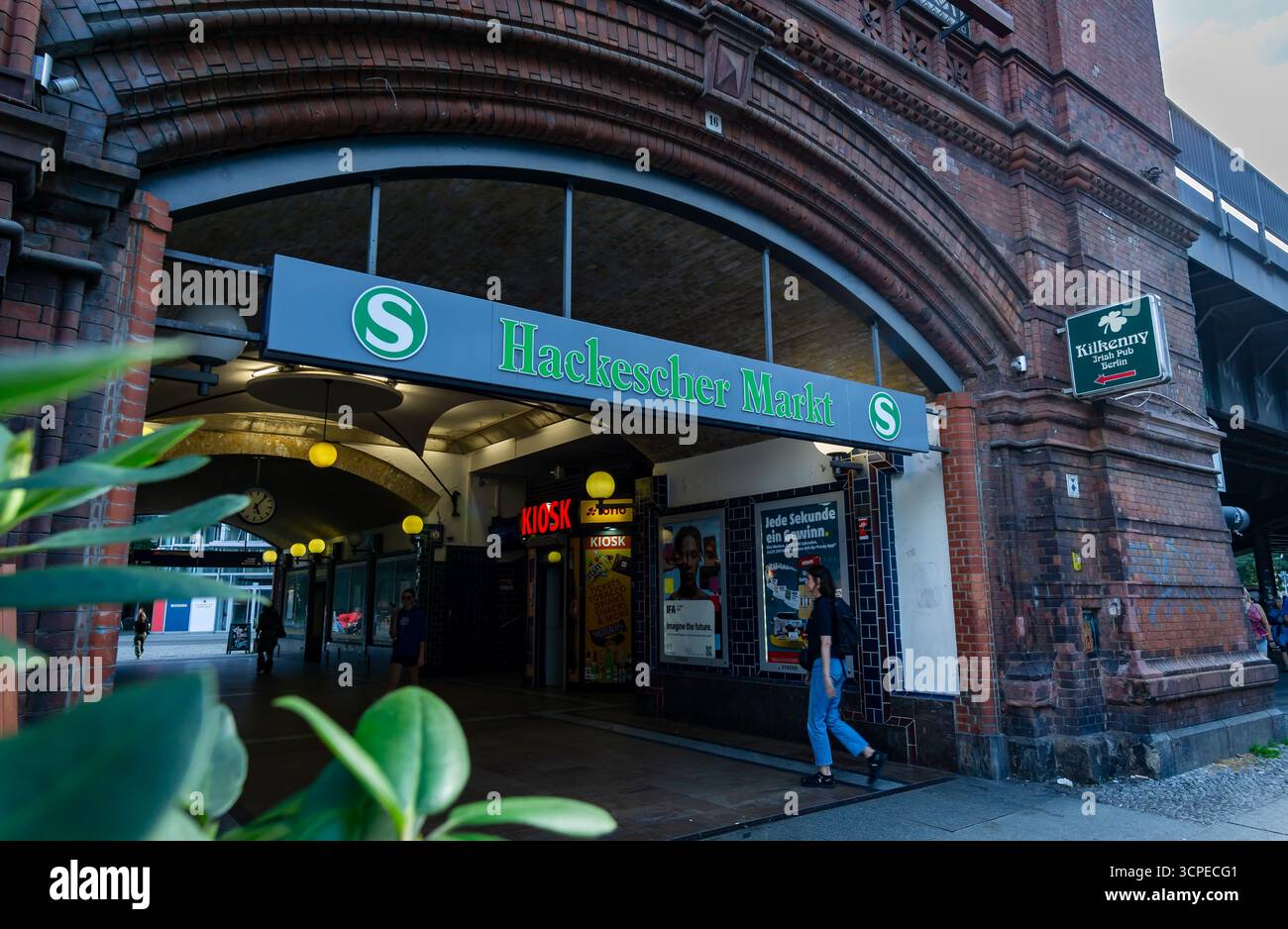 Blick auf den historischen S-Bahnhof Hackescher Markt in Berlin mit Fußgängern, Kiosk und Ziegelbogen unter dem Eisenbahnviadukt. Stockfoto