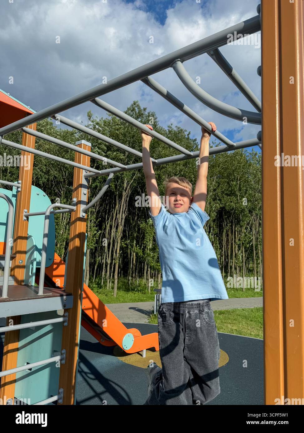 Teen Boy, der an einem hellen Sommertag auf einem Sportspielplatz an den Pull-up-Bars trainieren kann, Fitness- und Aktivitätskonzept - Smartphone-aufgenommenes Stockfoto