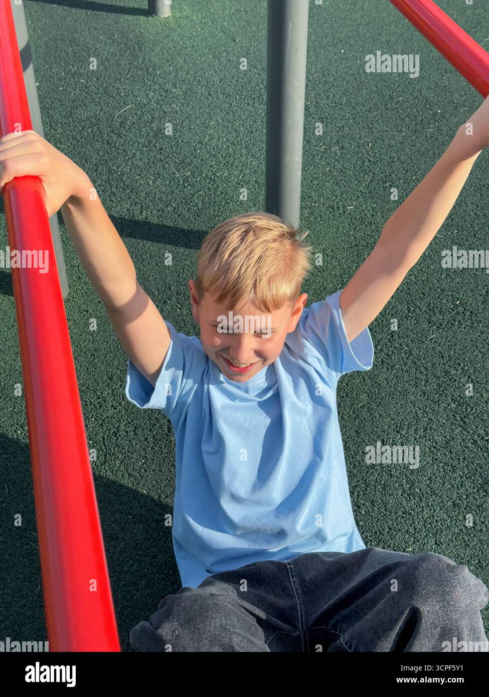 Teen Boy, der an einem sonnigen Sommertag auf einem Outdoor-Sportspielplatz an einem Pull-up-Bars trainiert, Fitness- und sportliches Aktivitätskonzept - Smartphone-aufgenommenes Stockfoto