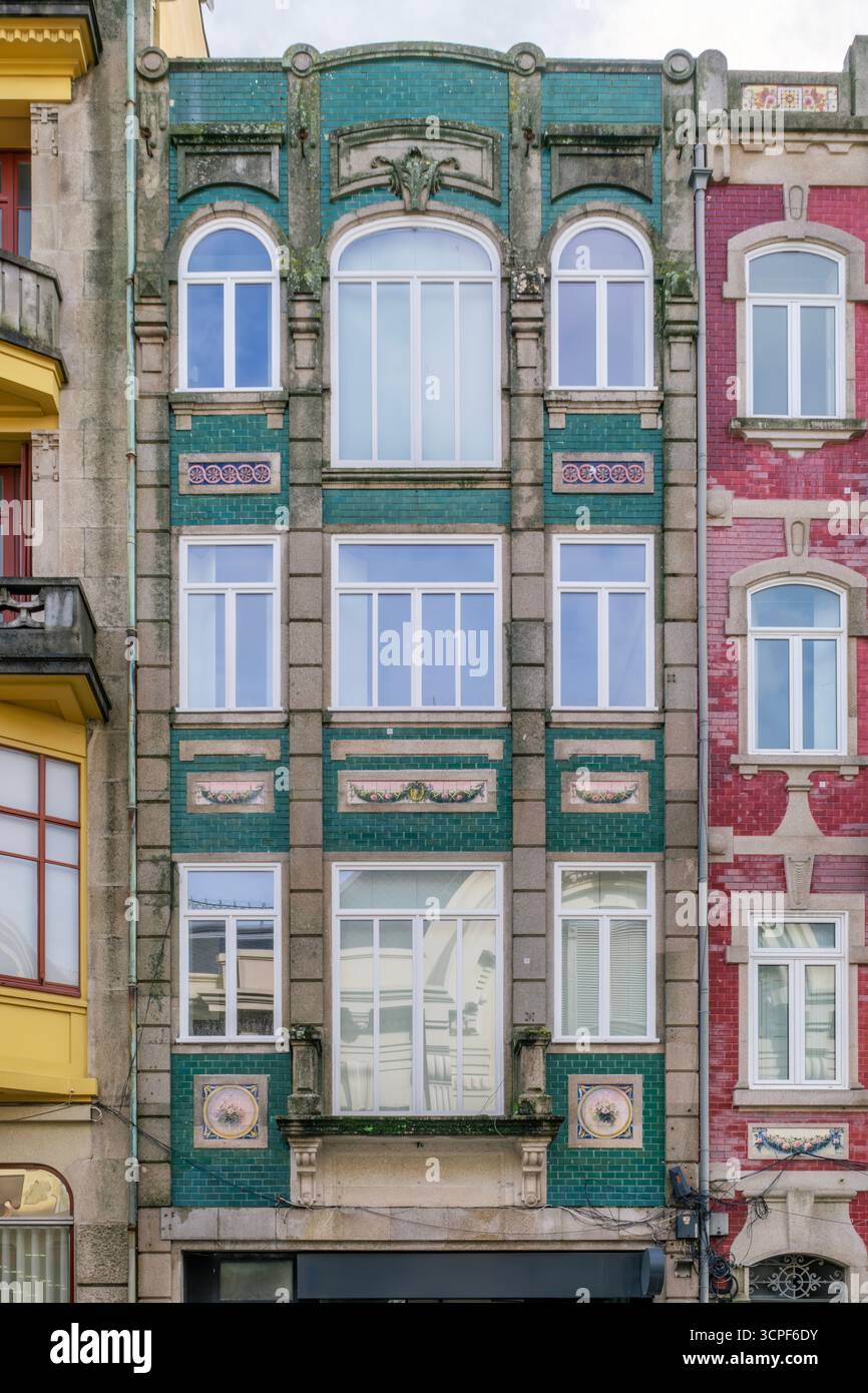 Vertikale Fassade des Porto-Gebäudes mit hellgrünen und gelben emaillierten Azulejo-Fliesen und symmetrischen Fenstern in Portugal. Historische Architektur, Keramik Stockfoto