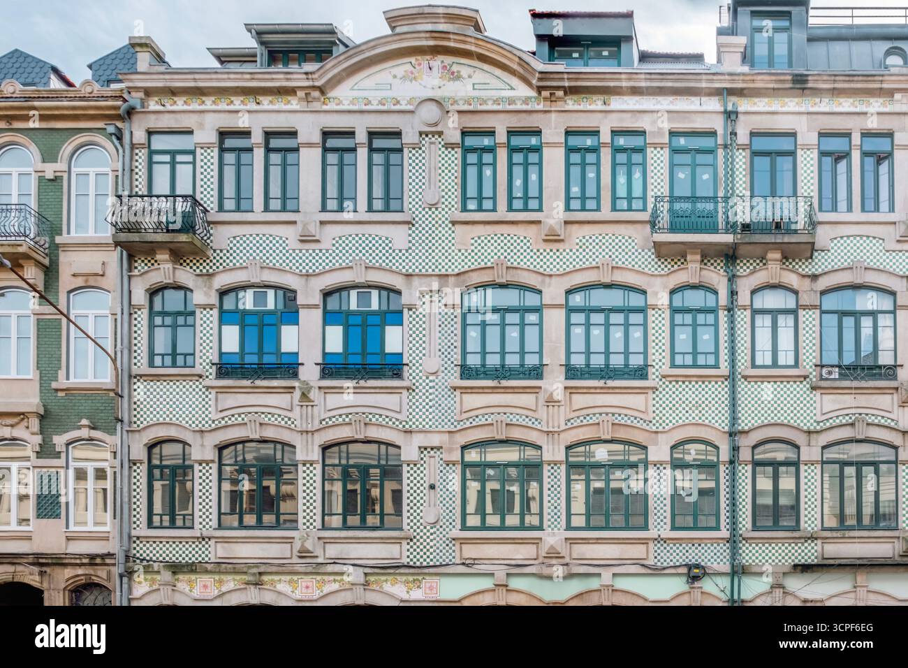 Breite Fassade des Porto-Gebäudes mit grün-weiß karierten Azulejo-Tiling, verzierten Steindetails und grünen Fensterrahmen. Historische Innenstadt Stockfoto