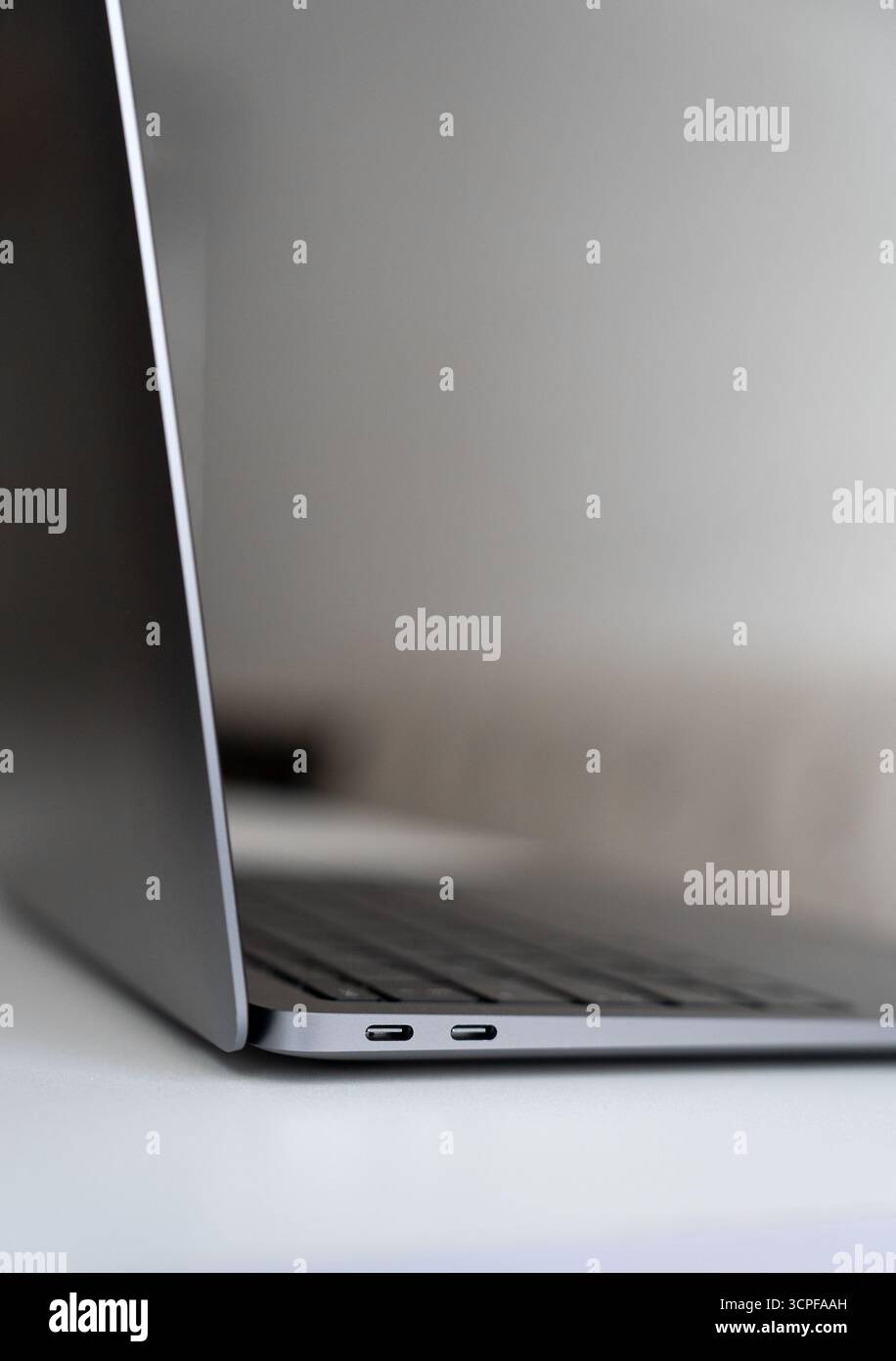 Vertikales Foto des Laptops, der aufrecht auf dem weißen Schreibtisch steht. Konzept moderner Technologie, Fernarbeit und Geschäftstools. Stockfoto