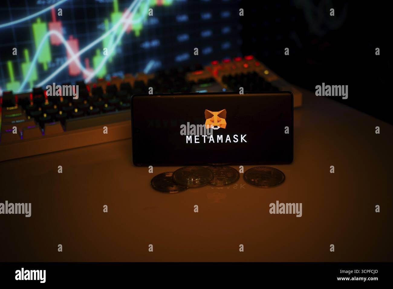 Telefon mit MetaMask mit Fuchs-Logo in der Nähe von Münzen und Marktdaten, verknüpft mit Krypto-Nutzung Stockfoto