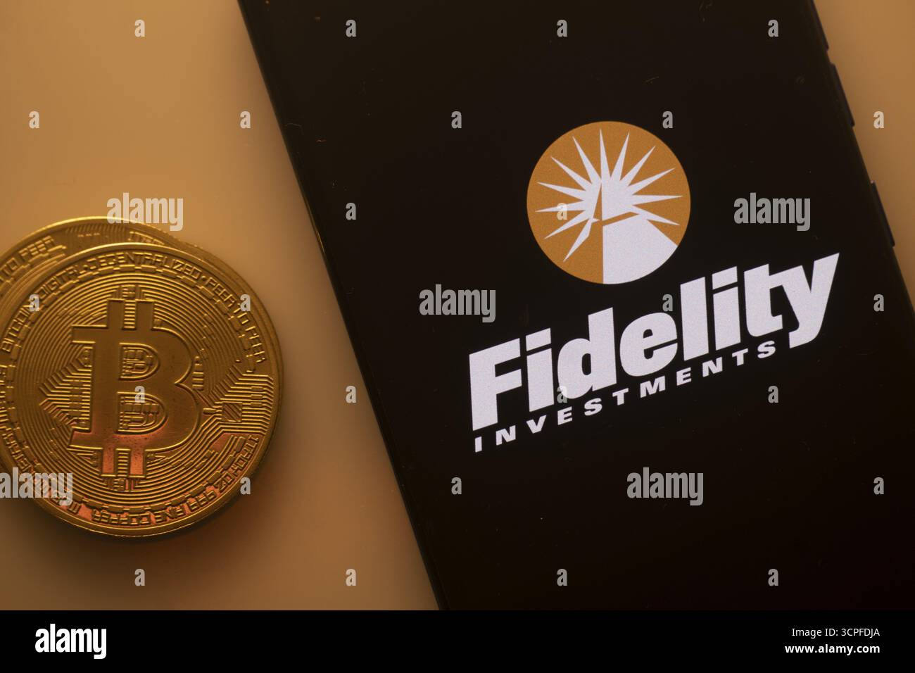 Fidelity Investments Logo auf dem Telefon neben Bitcoin, das Finanzdienstleistungen und Investitionen hervorhebt Stockfoto