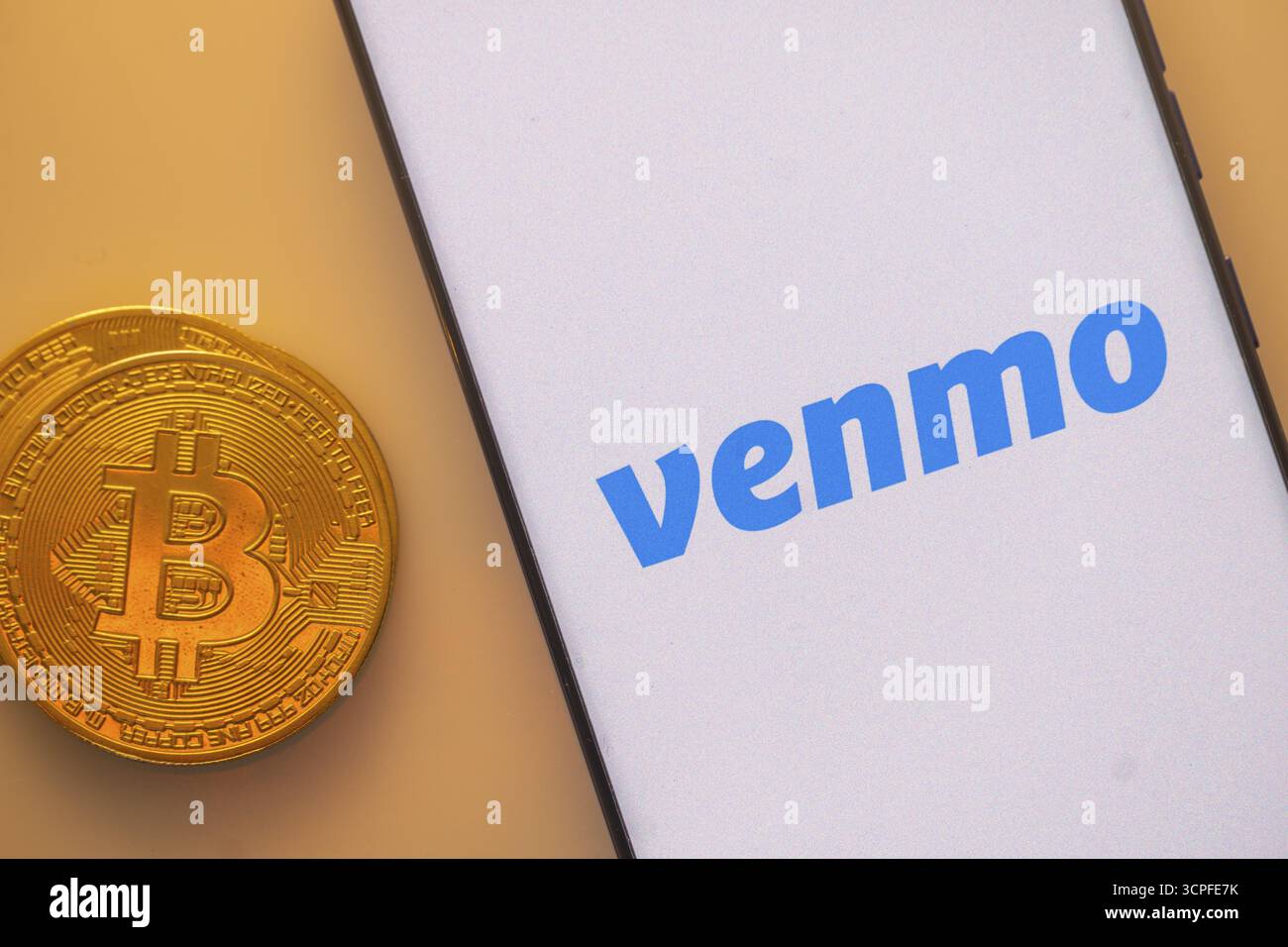 Bitcoin-Münze in der Nähe des Smartphones mit dem Venmo-Logo auf einem weißen Bildschirm Stockfoto