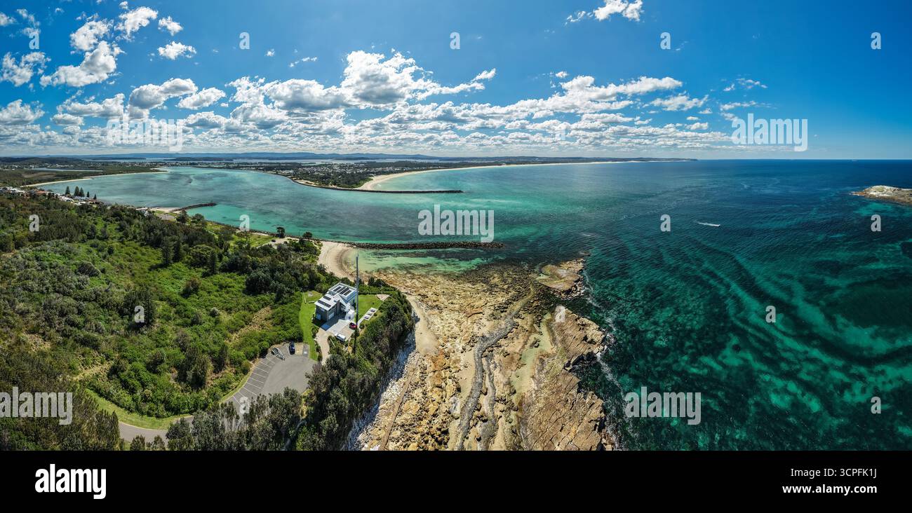 Aus der Vogelperspektive treffen Sie auf das türkisfarbene Wasser auf felsige Küsten und üppige grüne Landzungen, die die malerische Schönheit der Küste, Swansea, New South Wales, enthüllen Stockfoto