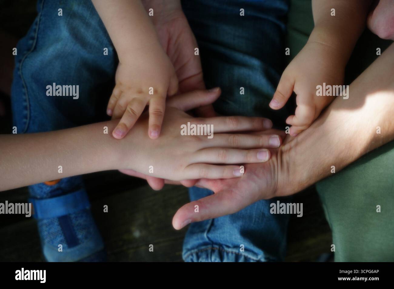 Nahaufnahme mehrerer Hände unterschiedlicher Größe, die übereinander platziert sind und Teamwork und Verbindung symbolisieren. Das Bild hebt Unity und collabora hervor Stockfoto