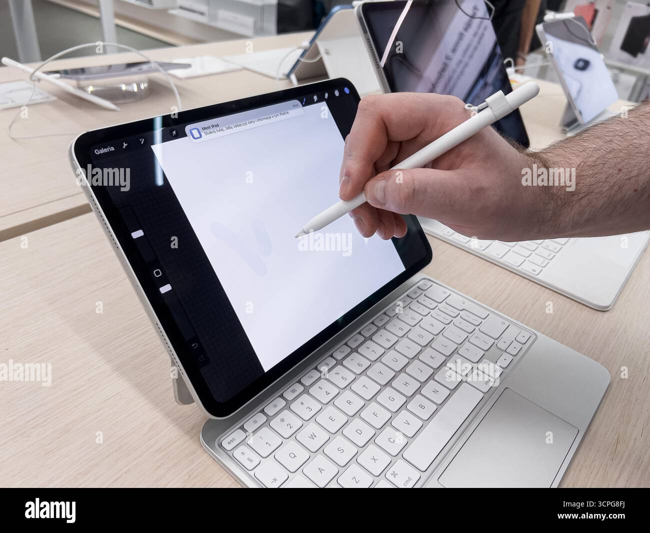 Poznan, Polen – 20. September 2025: Nahaufnahme einer Hand, die mit einem Apple iPad interagiert, mit dem Bleistift für digitales Design auf einem hellen Ladendisplay Stockfoto