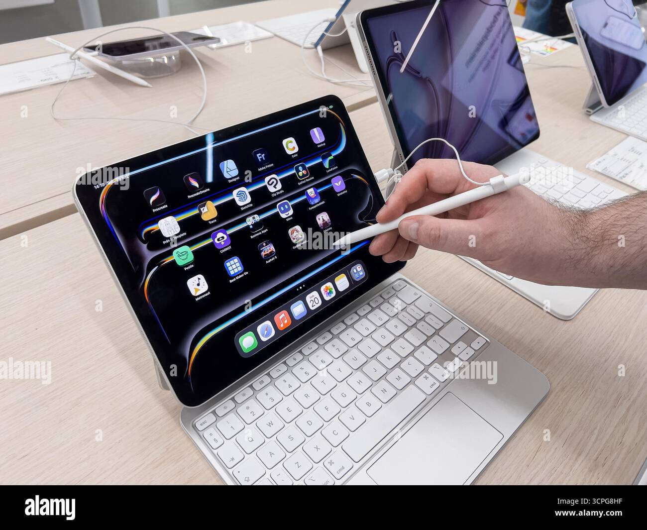 Poznan, Polen – 20. September 2025: Handbedienung des Apple Pencil auf dem Apple iPad mit Magic Keyboard, Navigation in verschiedenen Anwendungen, Hervorhebung der Technologie Stockfoto