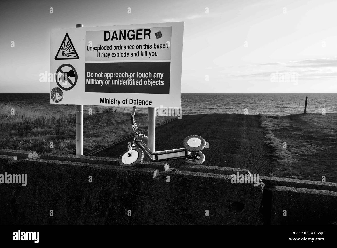 Reflektierende, farbenfrohe Warnzeichen für schwere Küsten- und Straßenerosion sowie Gefahrenzeichen für nicht explodierte Kampfmittel aus dem vergangenen Weltkrieg, Aldbrough. Stockfoto