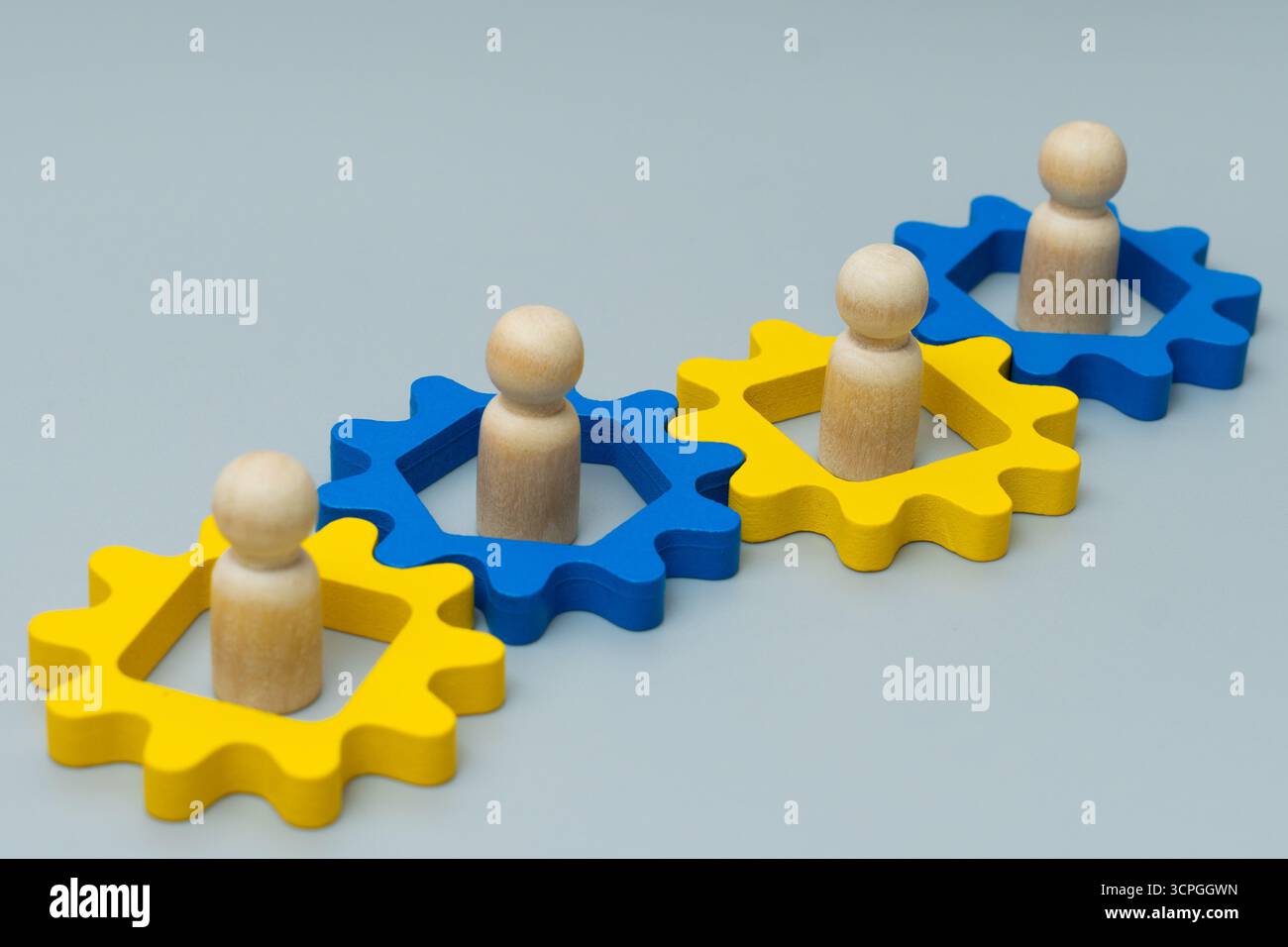 Holzfiguren in miteinander verbundenen Zahnrädern. Teamarbeit, Zusammenarbeit und die Vernetzung des Arbeitskonzepts. Stockfoto