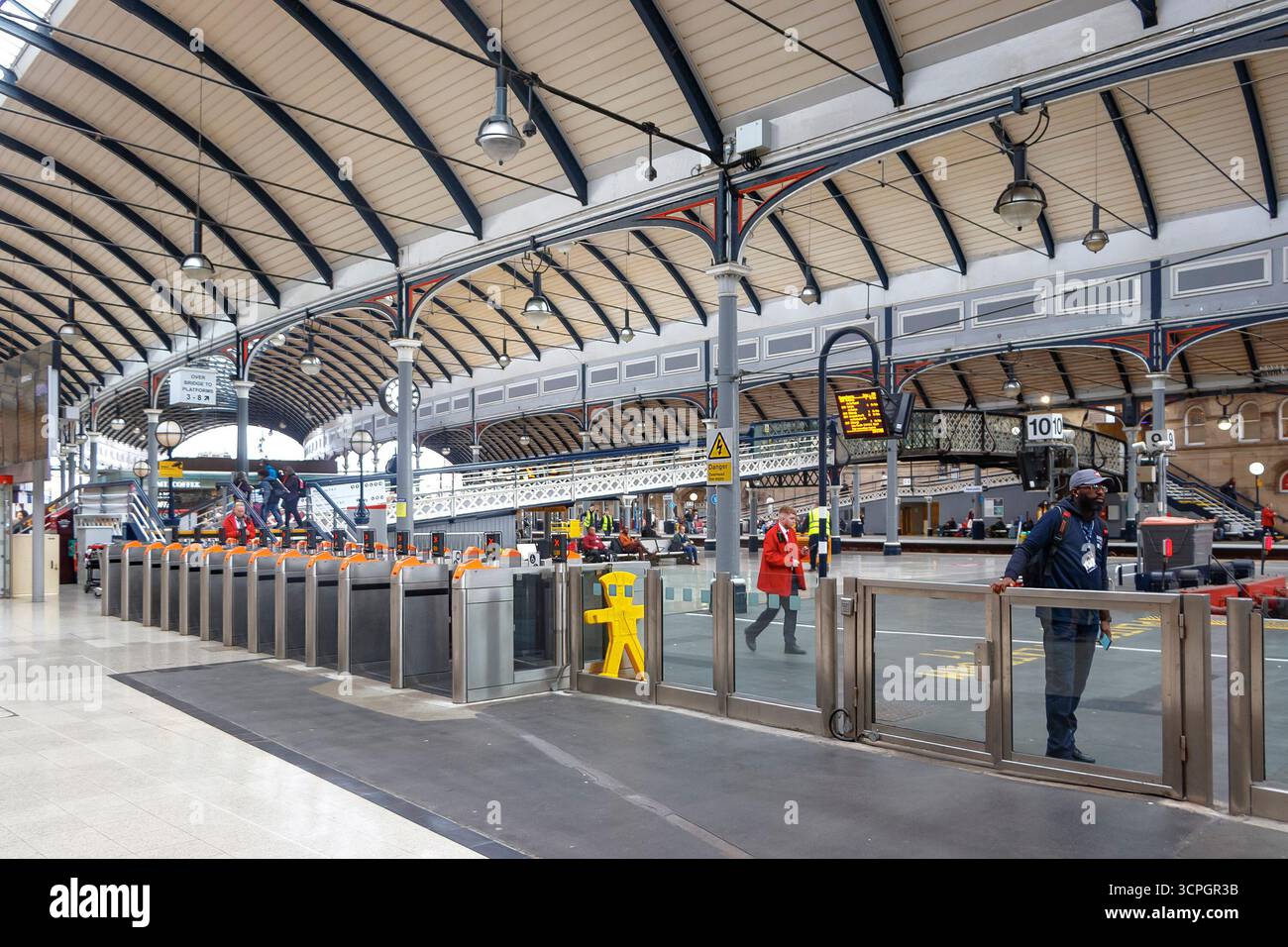 Innenansicht eines belebten Bahnhofs von newcastle upon tyne mit kunstvollen Eisenarbeiten, Bogendach und Menschen, die in der Nähe von Ticketschaltern und Bahnsteigen spazieren gehen Stockfoto