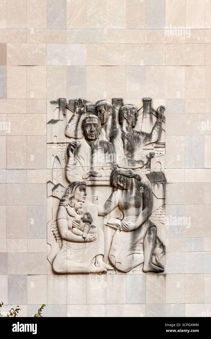 Wandschnitzerei an der Außenseite, die historische Figuren zeigt, die in einer antiken Umgebung an verschiedenen Aktivitäten beteiligt waren Stockfoto