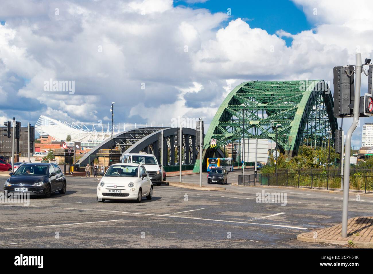 Urbane Szene mit Autos vor der Wearmouth Bridge unter einem bewölkten blauen Himmel in Sunderland, England Stockfoto