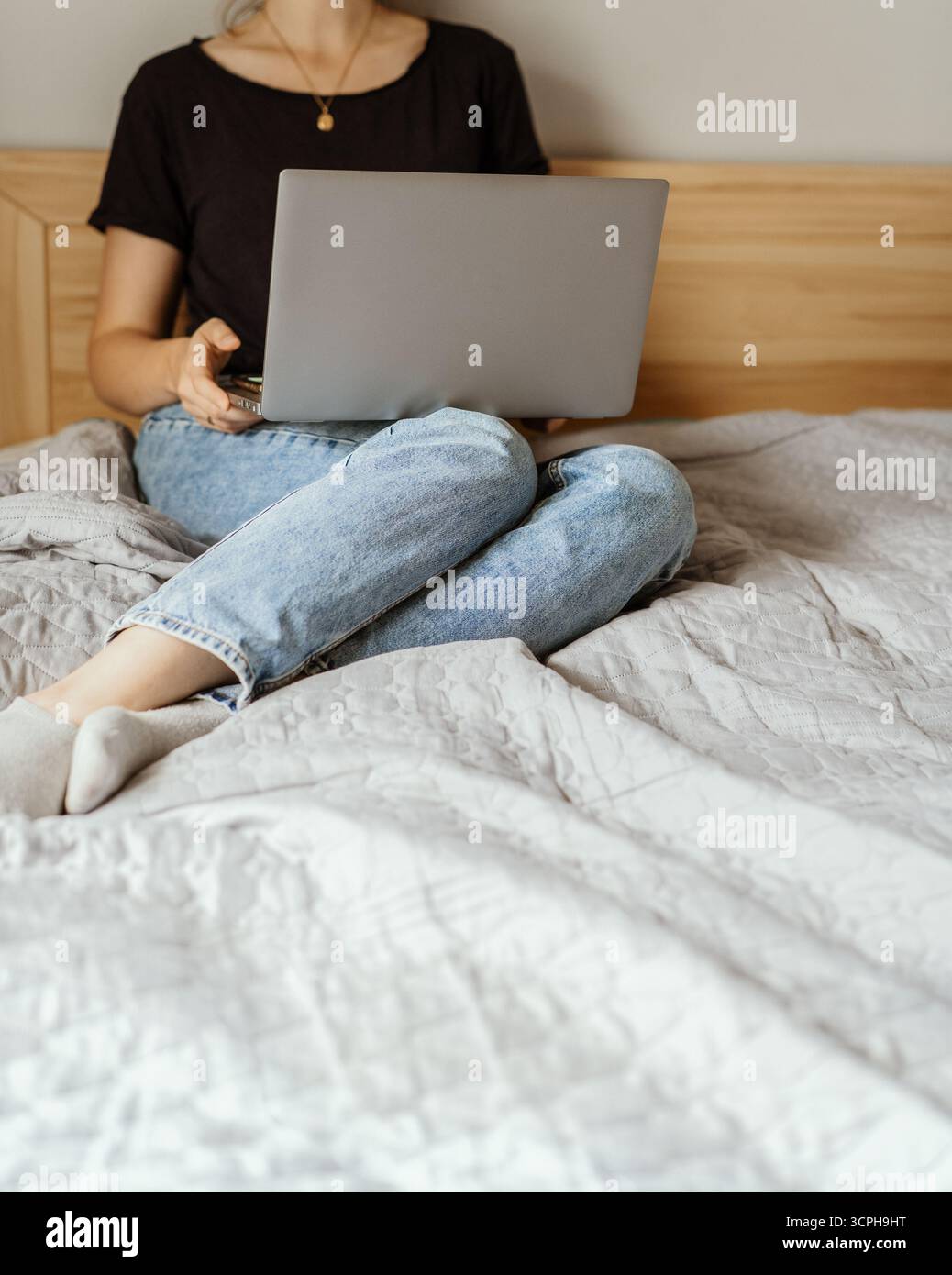Gesichtslose Frau mit Laptop auf dem Bett, lässig und offen ästhetisch Stockfoto