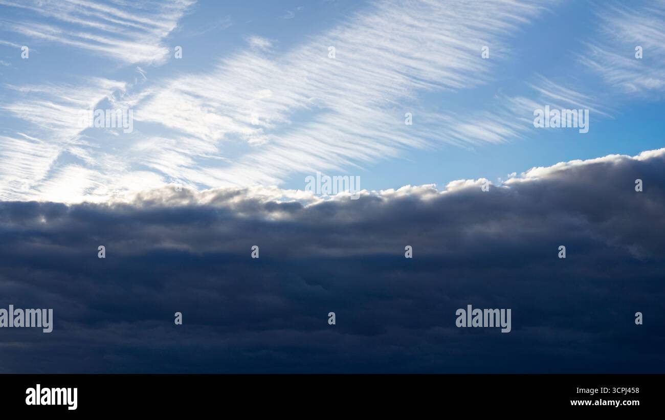 Dramatischer Himmel mit kontrastierenden hellen weißen Wolken über dunkler stürmischer Wolkenschicht in natürlicher Wetterlandschaft. Stockfoto