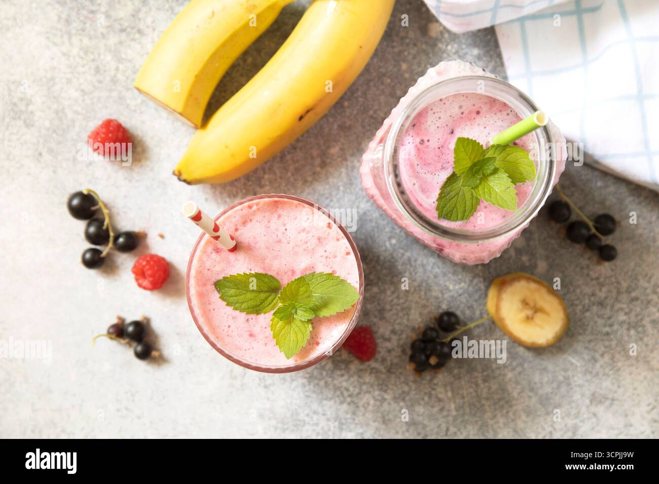 Erfrischender Smoothie aus Beeren und Bananen mit Minzgarnitur. Draufsicht flacher Hintergrund. Stockfoto
