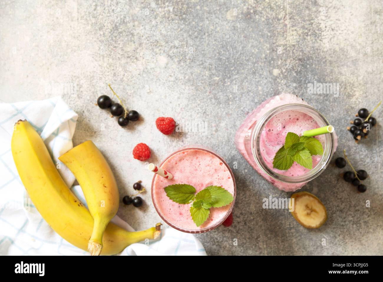 Erfrischender Smoothie aus Beeren und Bananen mit Minzgarnitur. Kopierbereich. Draufsicht flacher Hintergrund. Stockfoto
