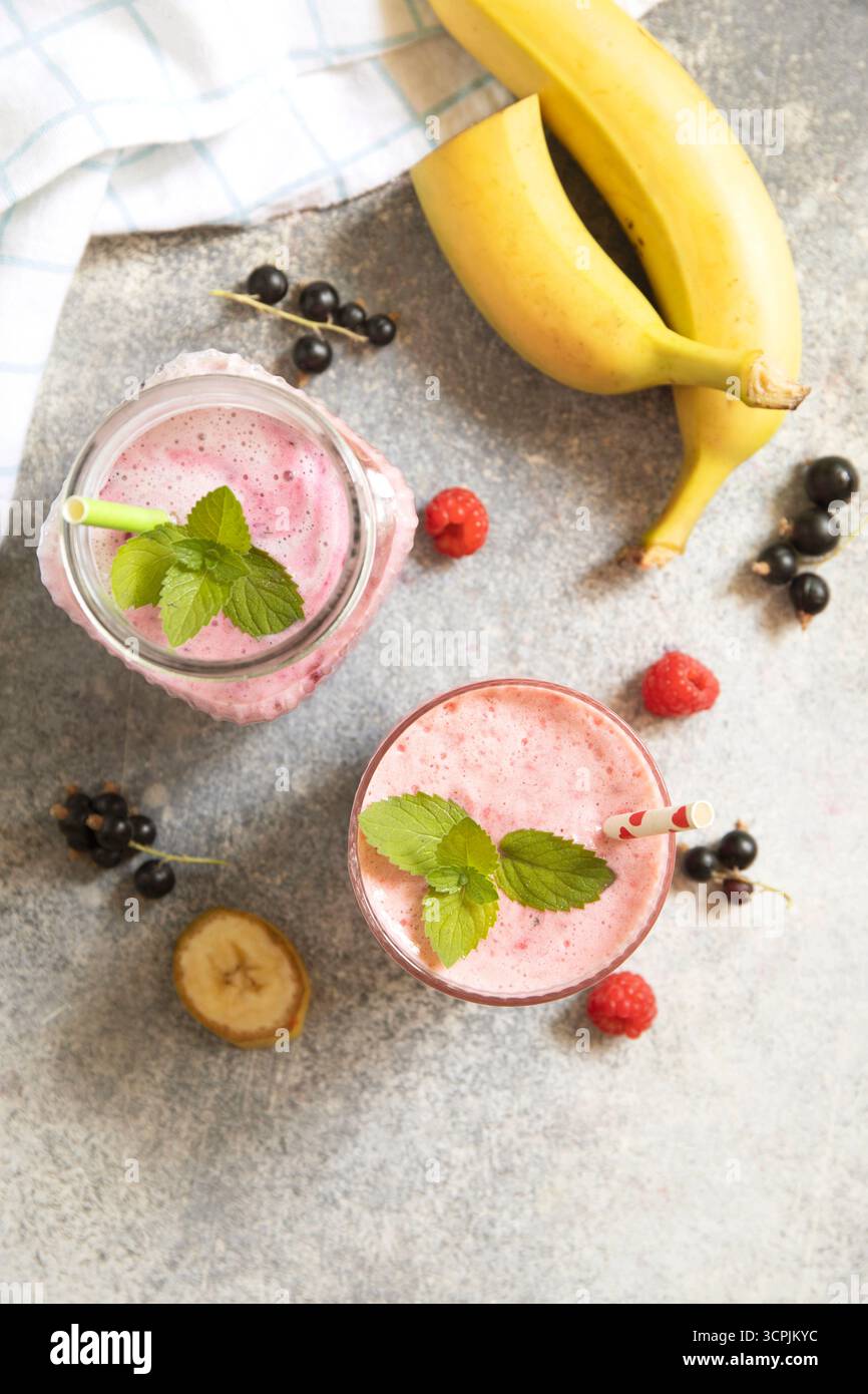 Erfrischender Smoothie aus Beeren und Bananen mit Minzgarnitur. Kopierbereich. Draufsicht flacher Hintergrund. Stockfoto