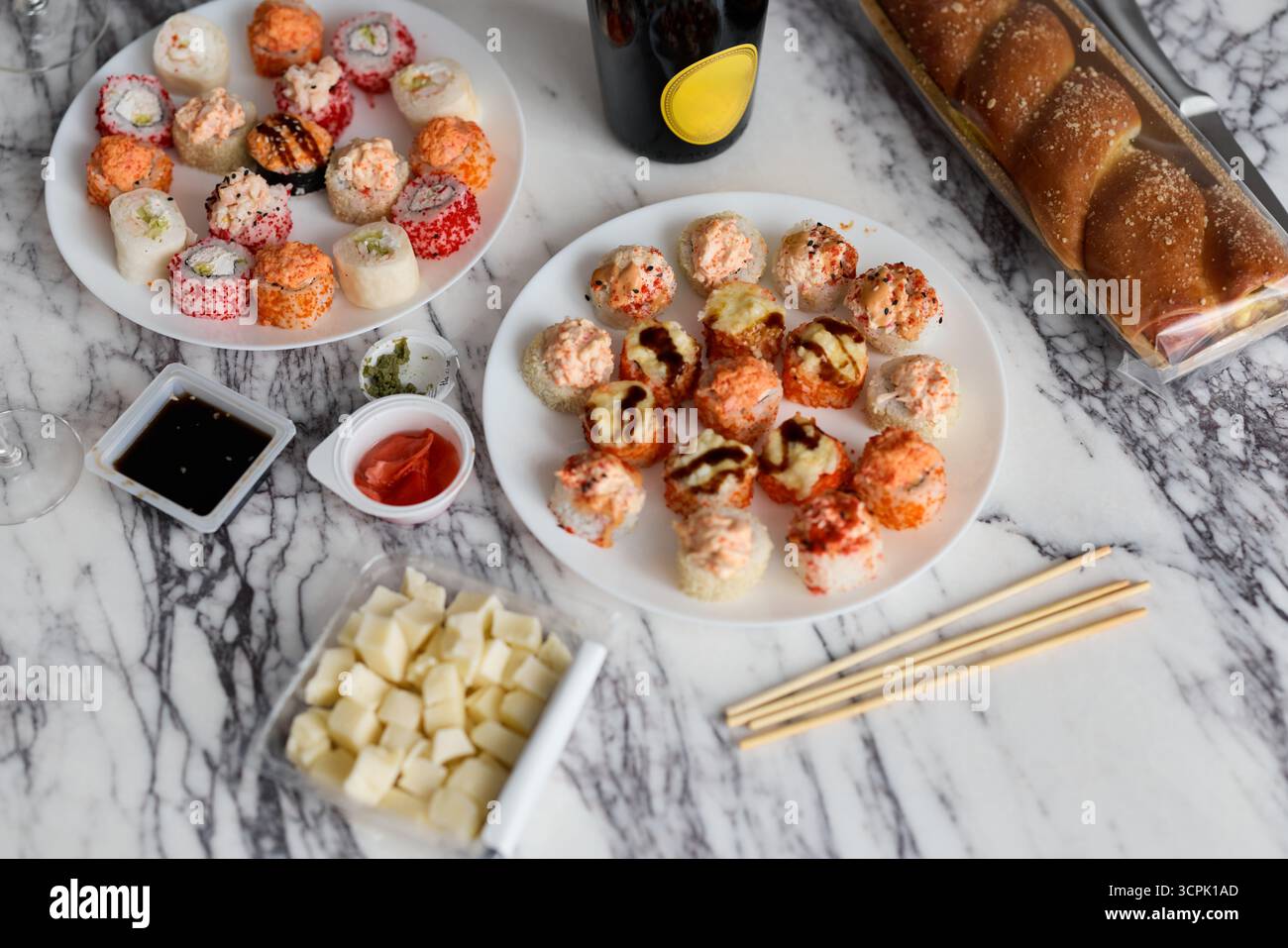 Genießen Sie köstliches Sushi und eine Auswahl an Snacks, die kunstvoll auf einem Marmortisch präsentiert werden Stockfoto