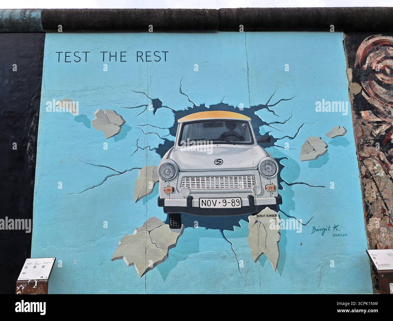 Wandmalerei eines Trabi (DDR Trabant Car), der in der East Side Gallery die Berliner Mauer durchbricht, symbolisiert Freiheit und deutsche Wiedervereinigung. Stockfoto