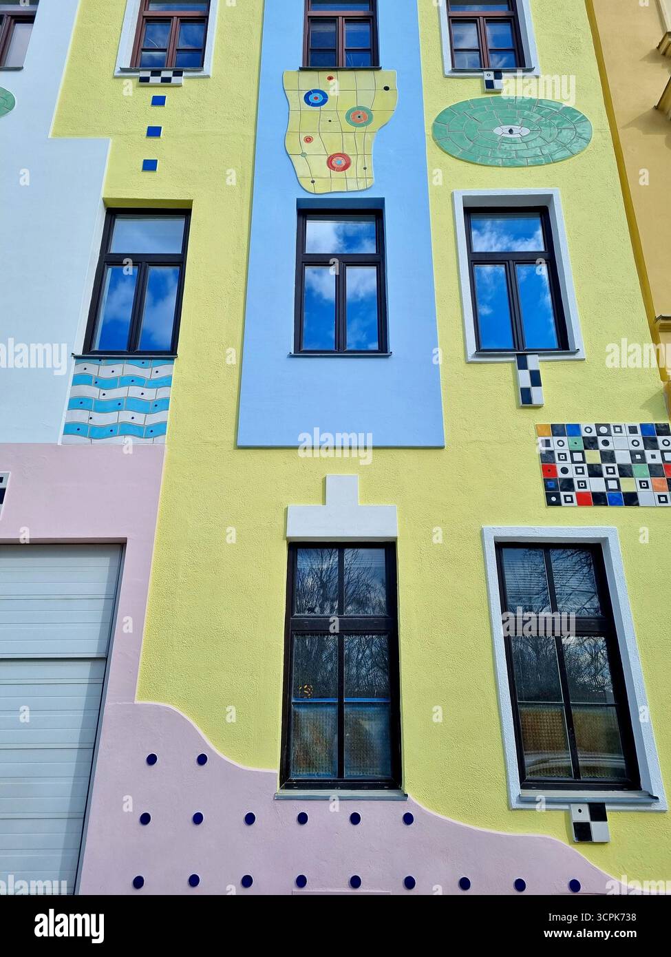Farbenfrohe, künstlerisch dekorierte Fassade eines alten Gebäudes mit wunderschönen blauen Himmelsreflexen in den Fenstern Stockfoto