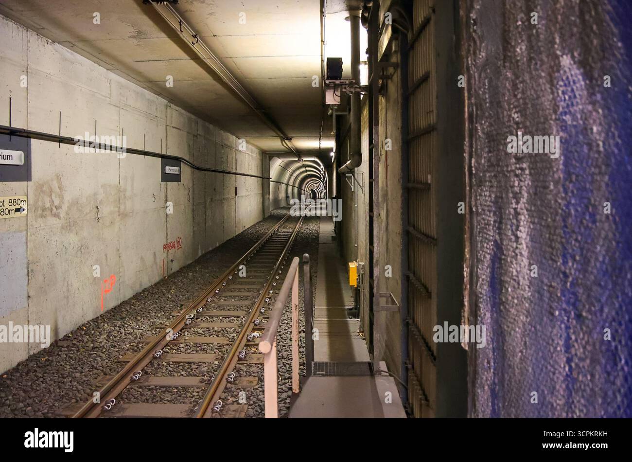 Bochum, Deutschland - 25. September 2025: Bahngleise, die tief in einen betonierten U-Bahn-Tunnel mit elektrischen Kabeln und Beleuchtung hineinreichen Stockfoto