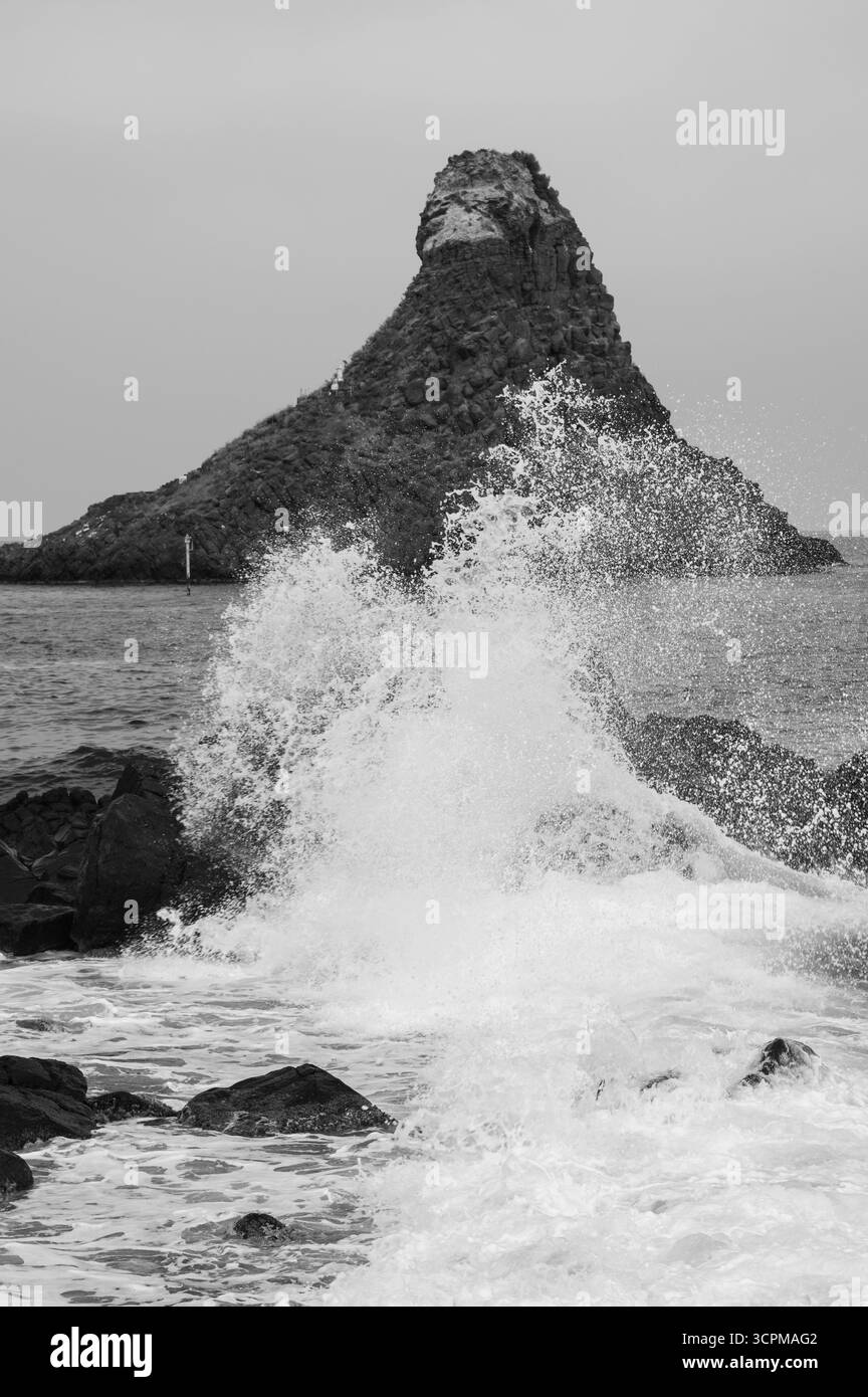 Wellenspritzer ahmen den Felsen im Hintergrund nach Stockfoto