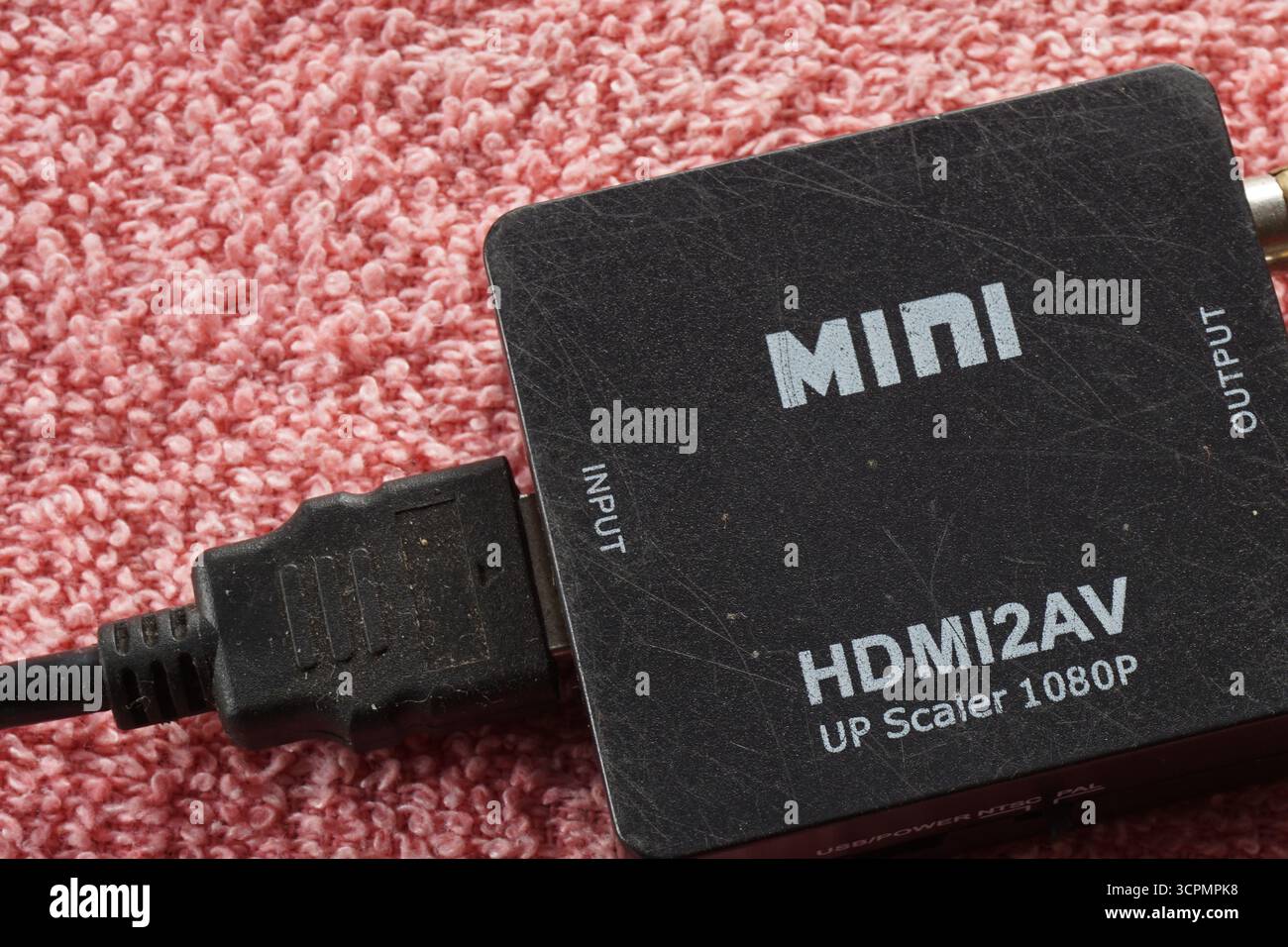 Nahaufnahme des schwarzen Mini-HDMI-Adapters auf rotem Hintergrund. HDMI für Multimedia-Anwendungen. Stockfoto