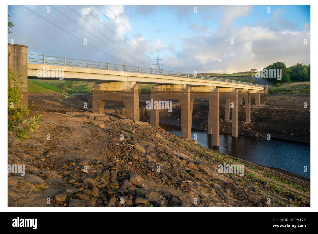 Niedrige Wasserstände am Baitings Reservoir, wobei die normalerweise untergetauchten Brückenfundamente freigelegt sind, was die Dürrebedingungen hervorhebt. Stockfoto