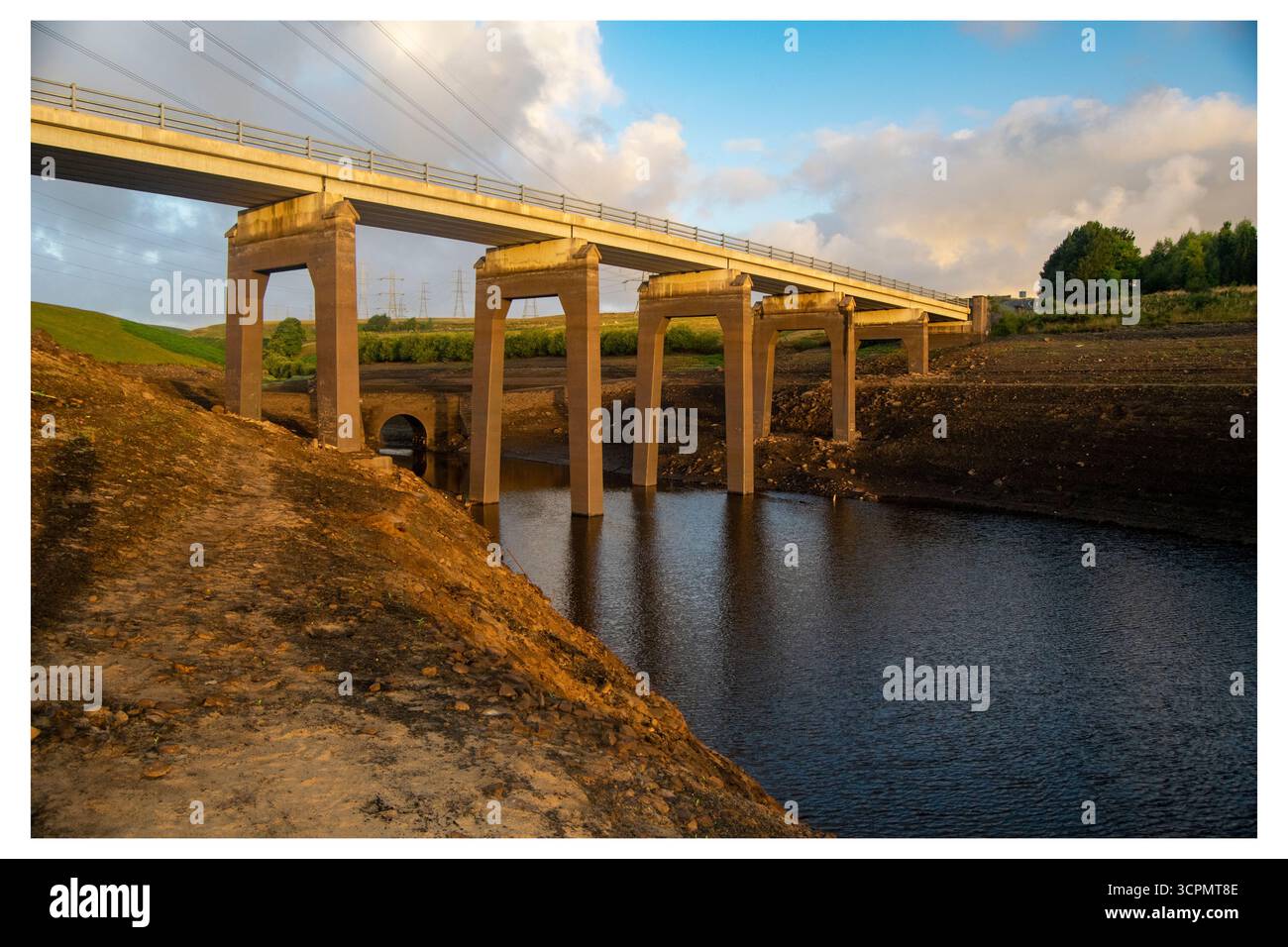 Niedrige Wasserstände am Baitings Reservoir, wobei die normalerweise untergetauchten Brückenfundamente freigelegt sind, was die Dürrebedingungen hervorhebt. Stockfoto