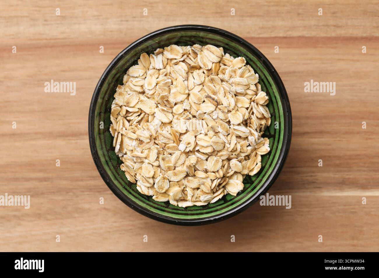 Schüssel mit Haferflocken auf Holztisch. Gesundes Bio-Ernährungskonzept. Natürliche Frühstückszutat. Diätetisches Lebensmittel mit Ballaststoffen und Kohlenhydraten Stockfoto
