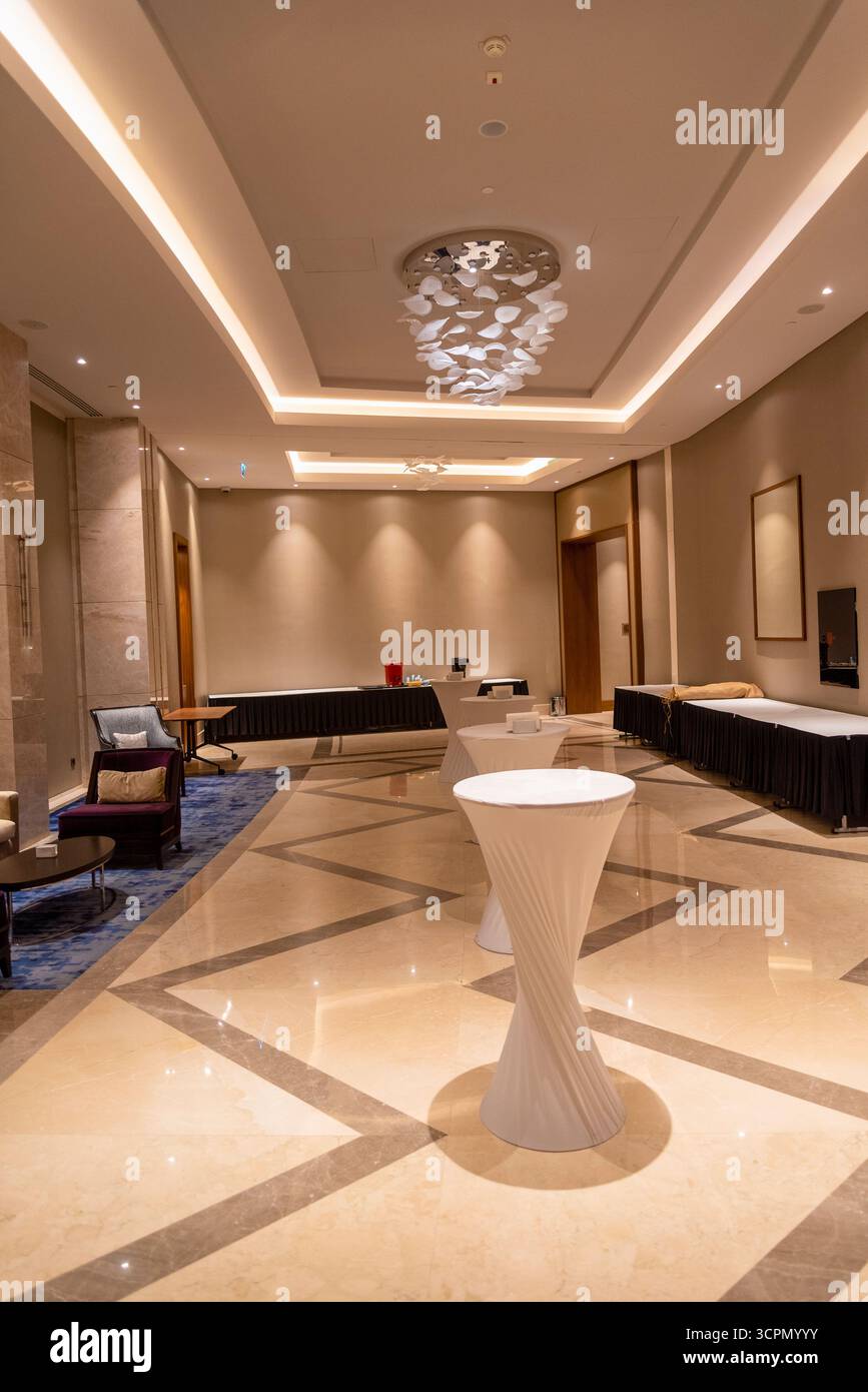 Ein geräumiger Veranstaltungsort mit moderner Einrichtung und Ambiente-Beleuchtung ist ideal für gesellschaftliche Veranstaltungen. Der polierte Boden spiegelt das stilvolle Designelement wider Stockfoto