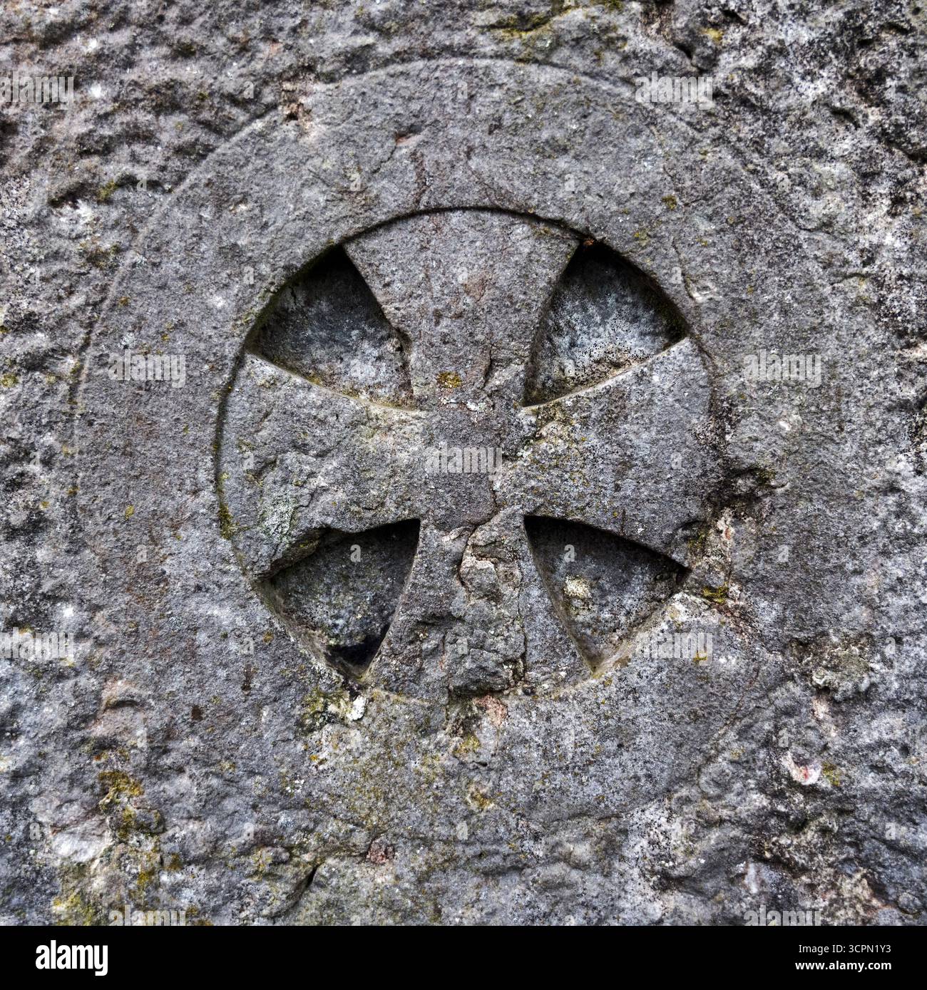 Verwitterte Steinschnitzerei eines Kreuzes auf einem alten Grabstein oder Monument, historisches christliches Erbe in England. Stockfoto