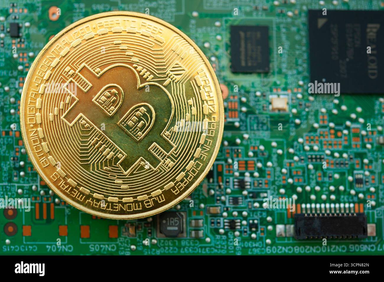 Goldene Bitcoin-Münze auf Computermotherboard, die Kryptowährungen-Mining und digitale Finanzen symbolisiert Stockfoto