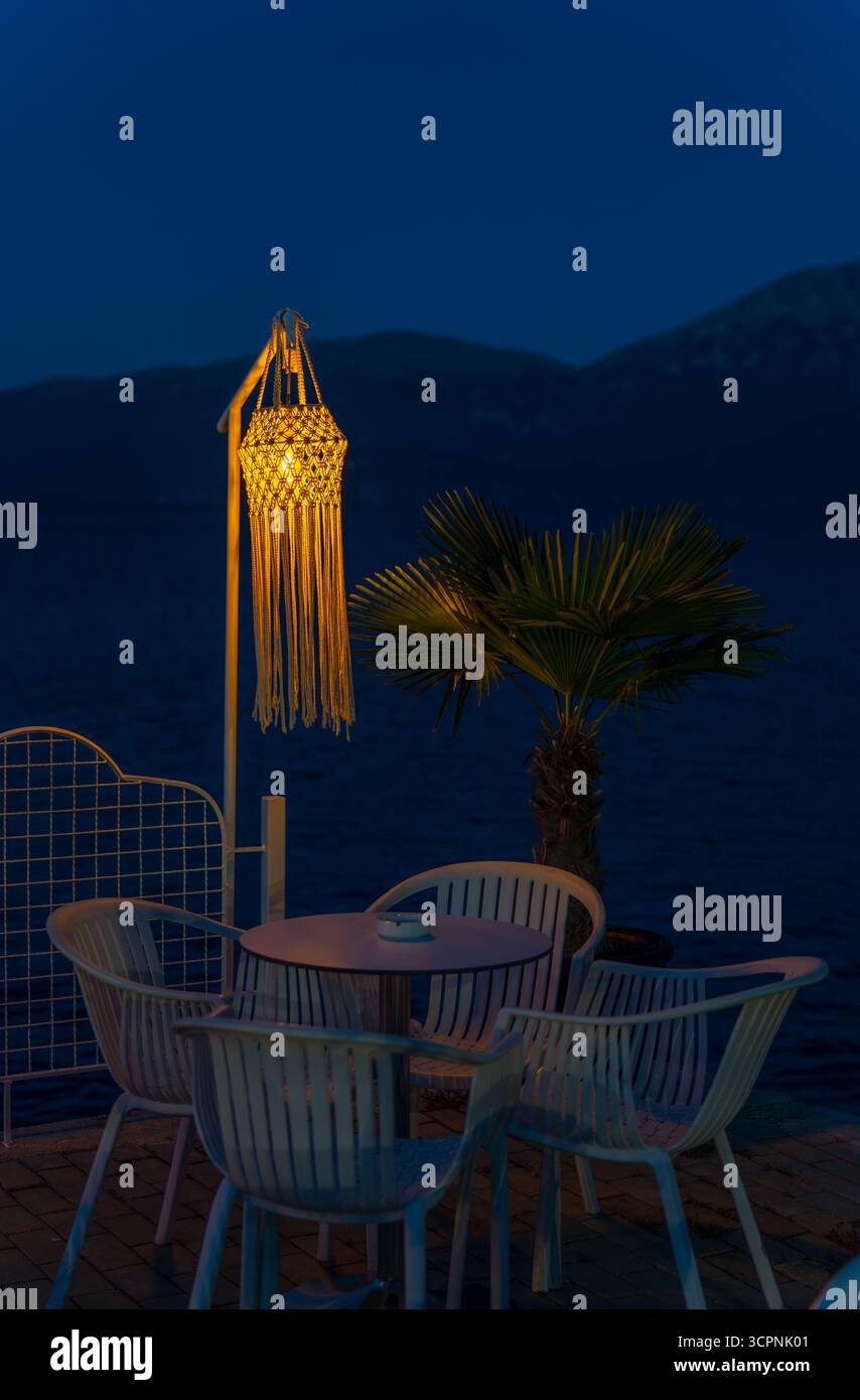 Gemütliche Sitzplätze am See mit warmem Laternenlicht am Ohridsee in Pogradec, Albanien, unter einem ruhigen blauen Abendhimmel Stockfoto