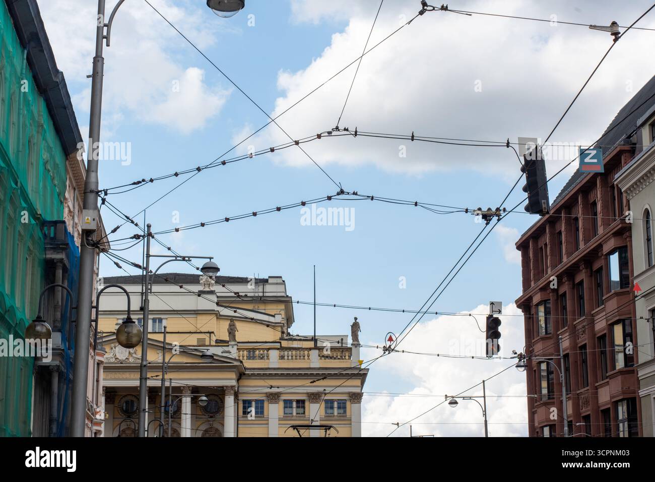 Historische Stadtkreuzung mit bunten Gebäuden, Straßenbahnleitungen und Ampeln vor blauem, bewölktem Himmel. Konzept des europäischen Stadttranspors Stockfoto