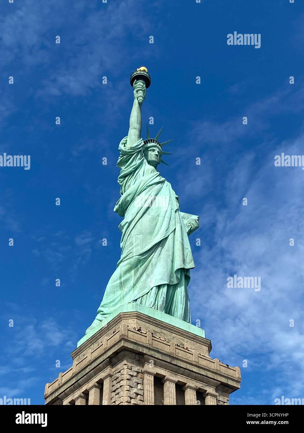 Freiheitsstatue gegen Blauen Himmel mit verstreuten Wolken in New York City - Smartphone-aufgenommenes Stockfoto